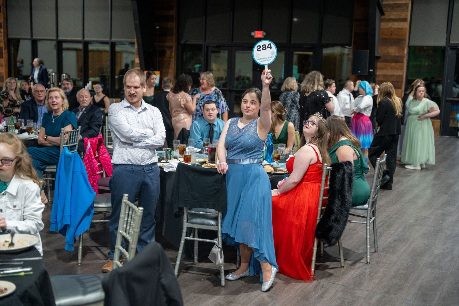 Wedding guests in blue bridesmaid dresses enjoy an outdoor reception at an elegant venue with modern design elements.