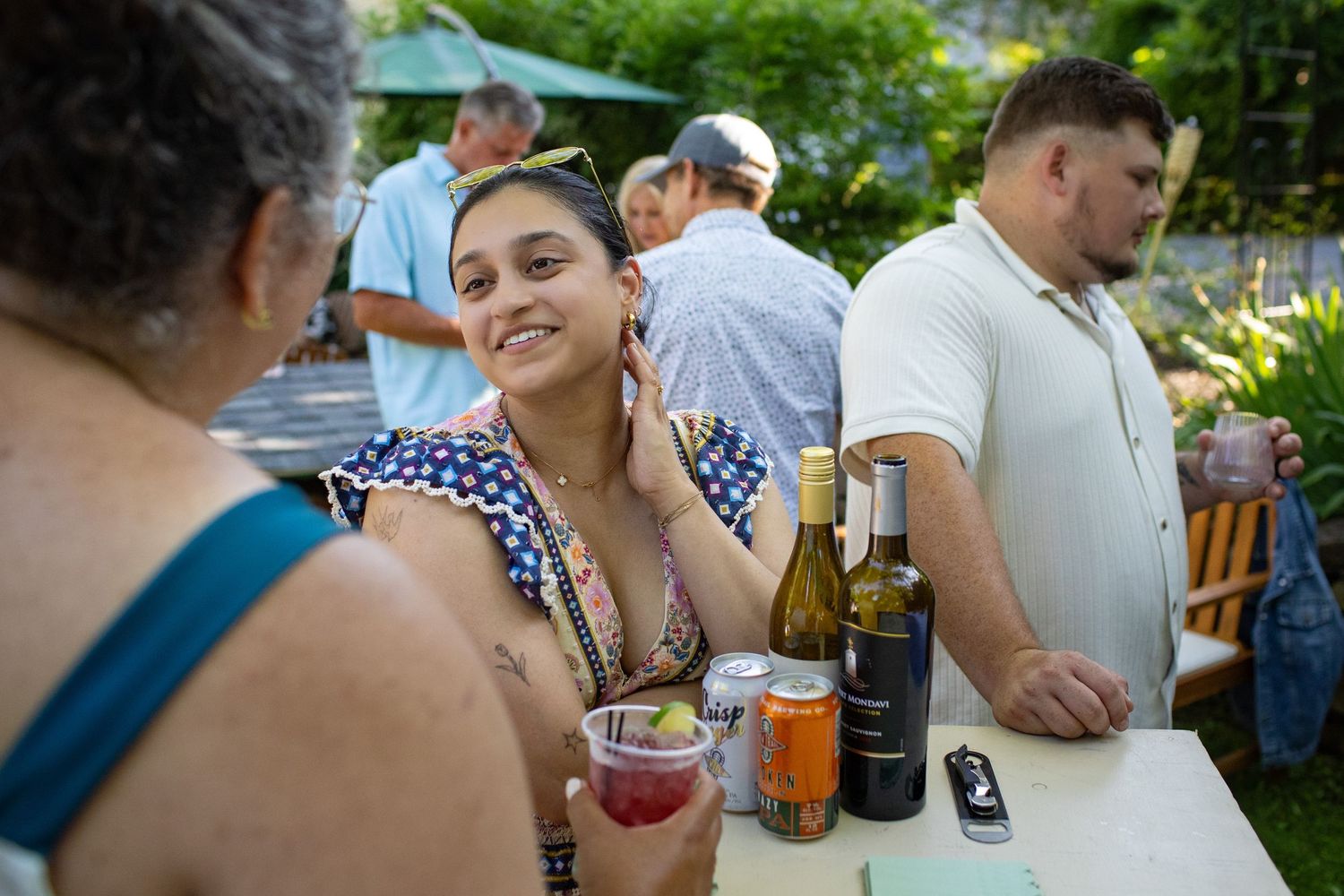 People enjoying drinks and conversation at an outdoor summer garden party gathering.