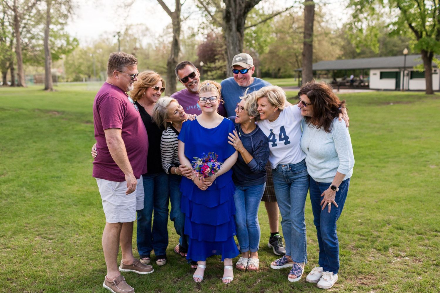 A group of people gather outdoors in a park for a casual photo together on a spring day.