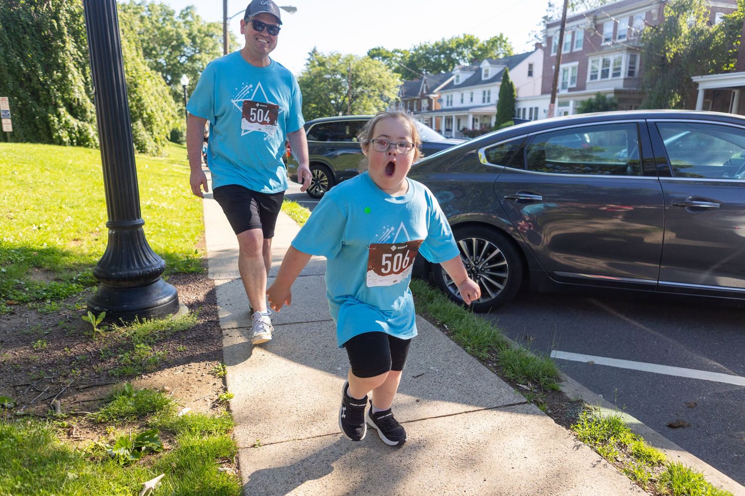 Two participants in blue shirts walking together during an outdoor charity event.