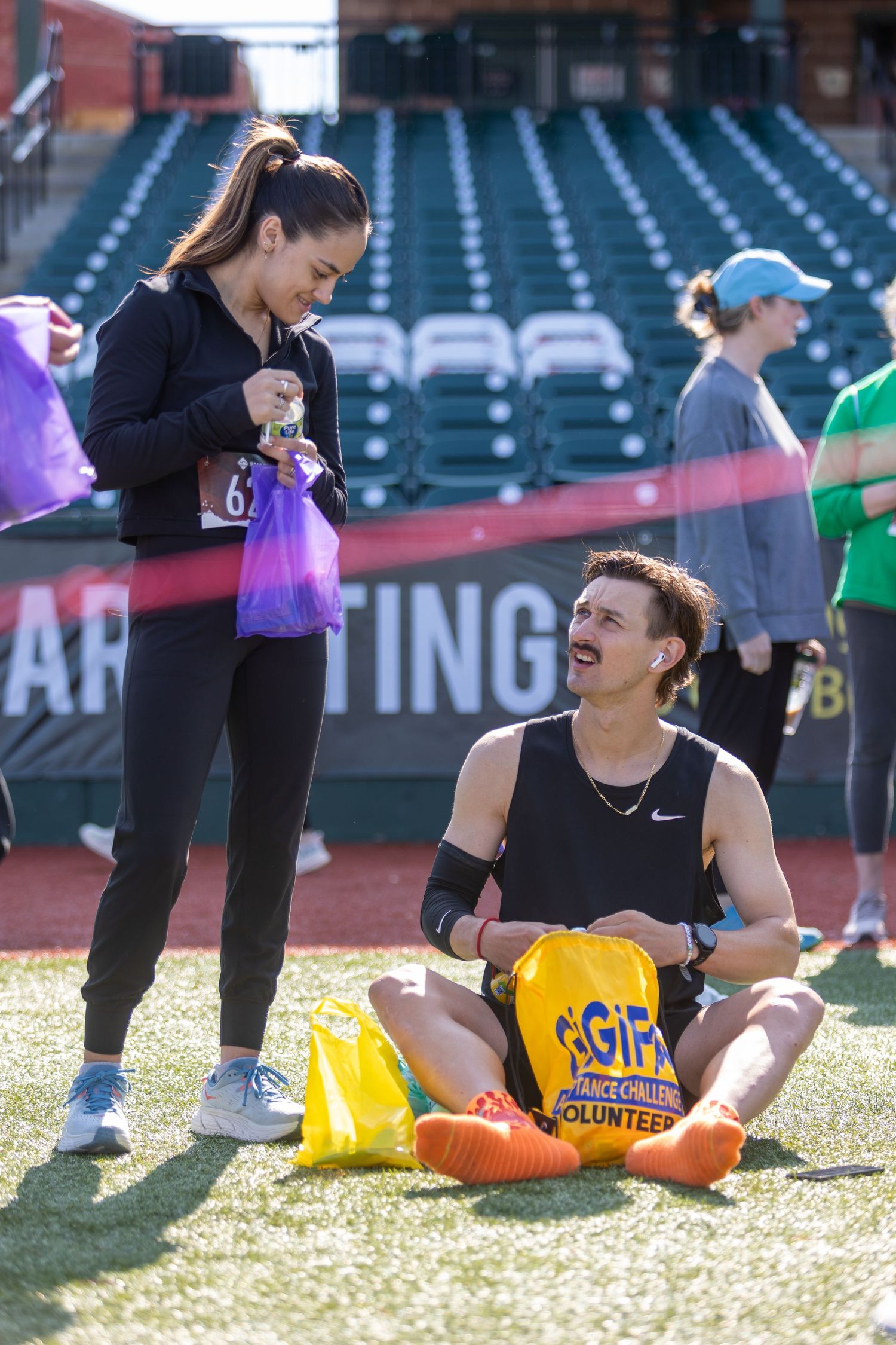 Athletes taking a break and enjoying snacks on baseball field during daytime event.