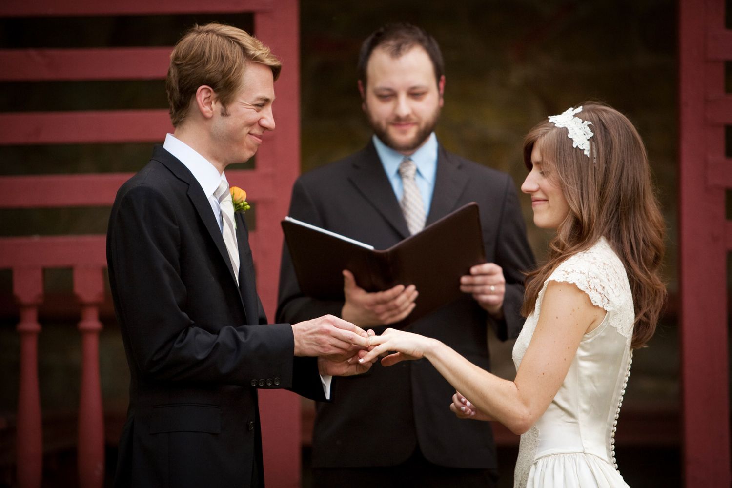 A solemn wedding ceremony unfolds with participants exchanging vows in a traditionally decorated indoor venue.