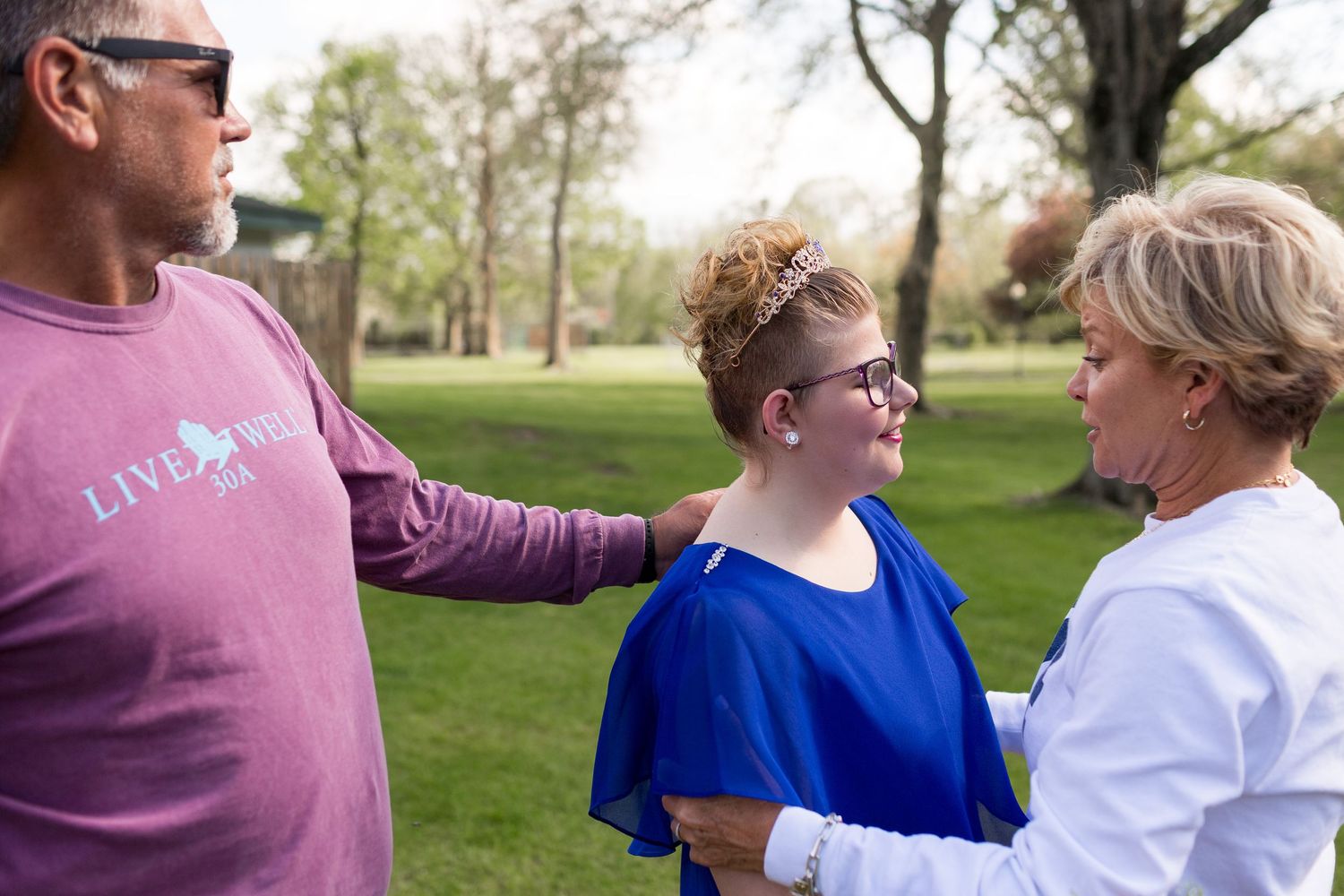 Three people having a conversation together in a park on a sunny day.