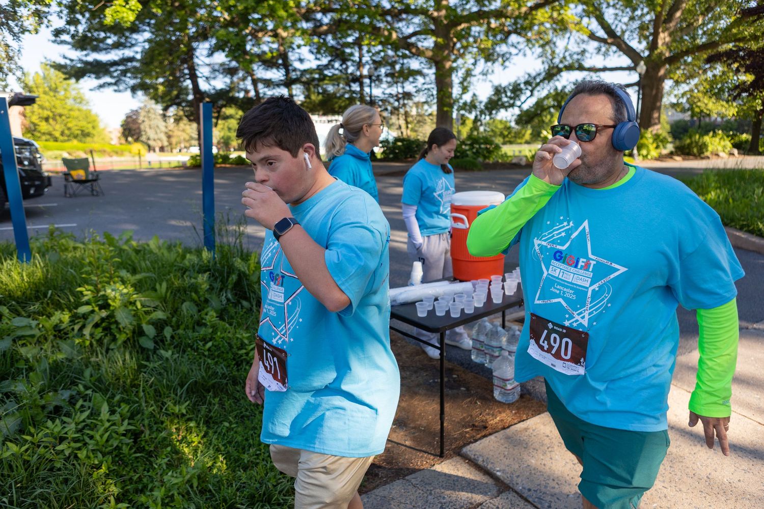 Participants in blue t-shirts gather outdoors during a community event on a sunny day.