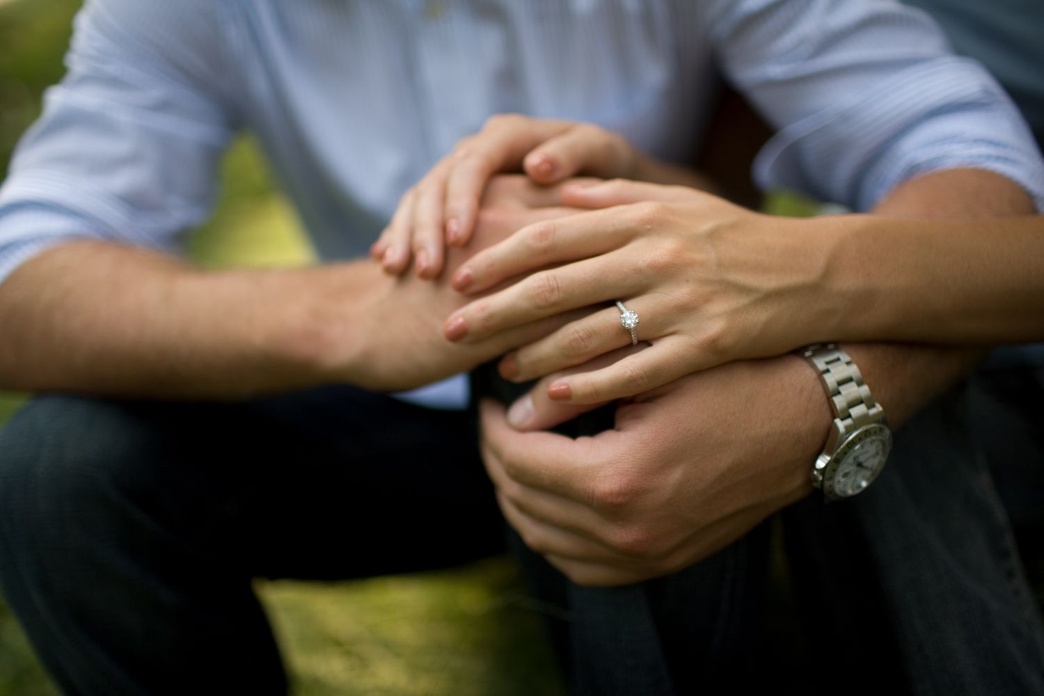 Close up of hands with engagement ring and watch showing tender moment.