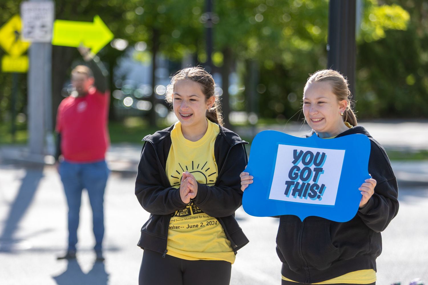 Participants holding encouraging signs while cheering during outdoor community event.