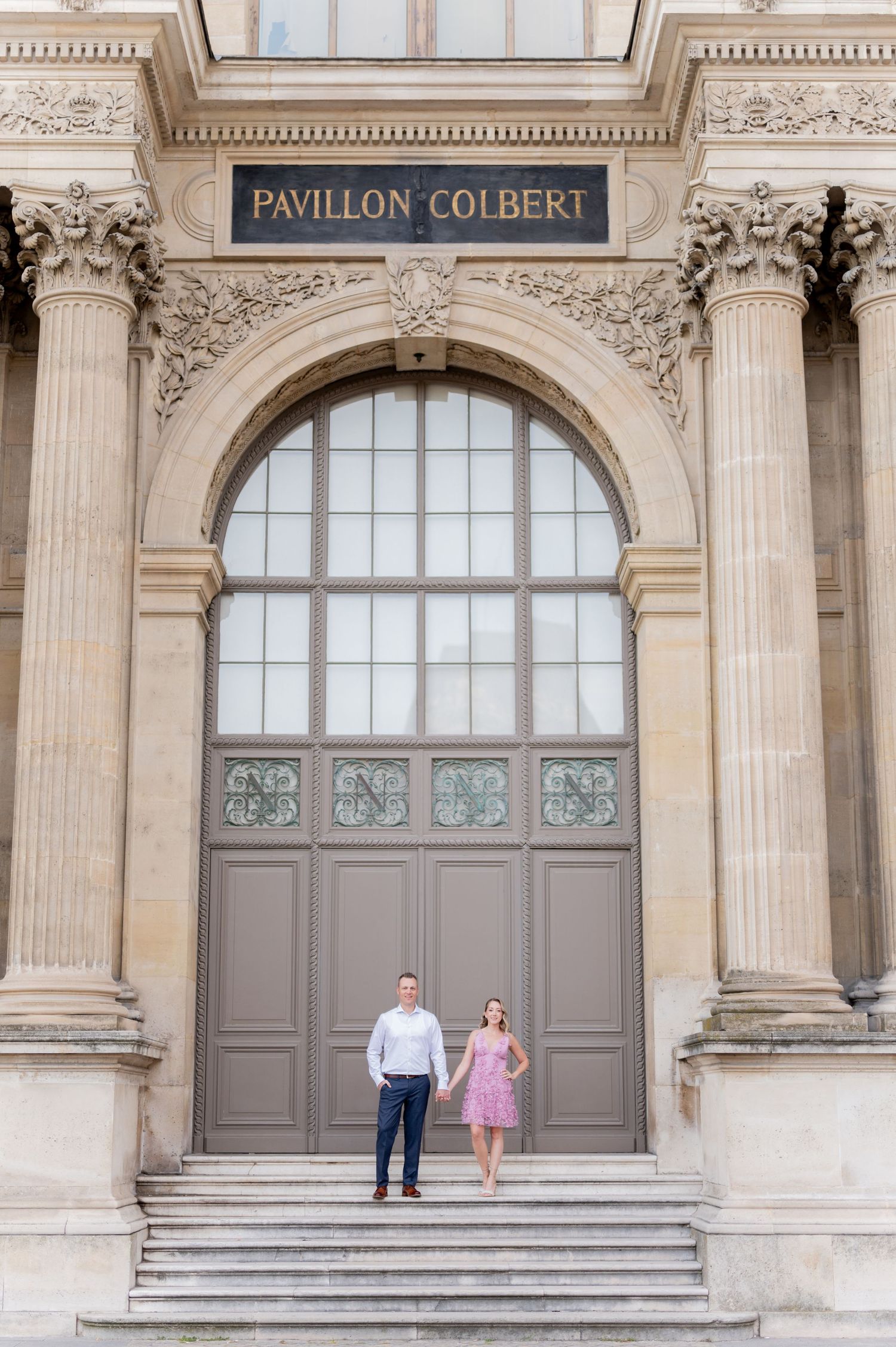 A couple stands on the steps of the historic Pavillon Colbert in Paris.