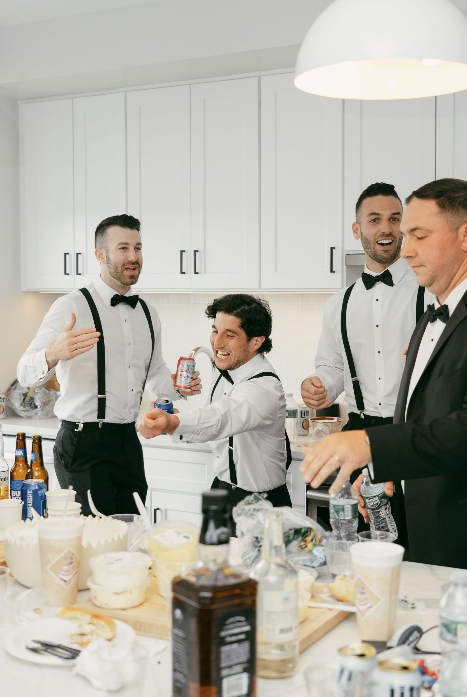 A group in formal attire gathers around a table with drinks and refreshments during what appears to be a celebratory event.
