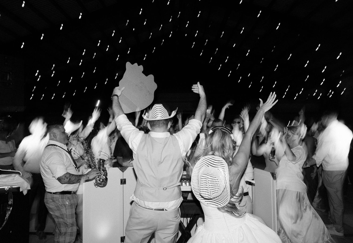 A vintage black and white photo of people dancing under twinkling lights at a celebration.