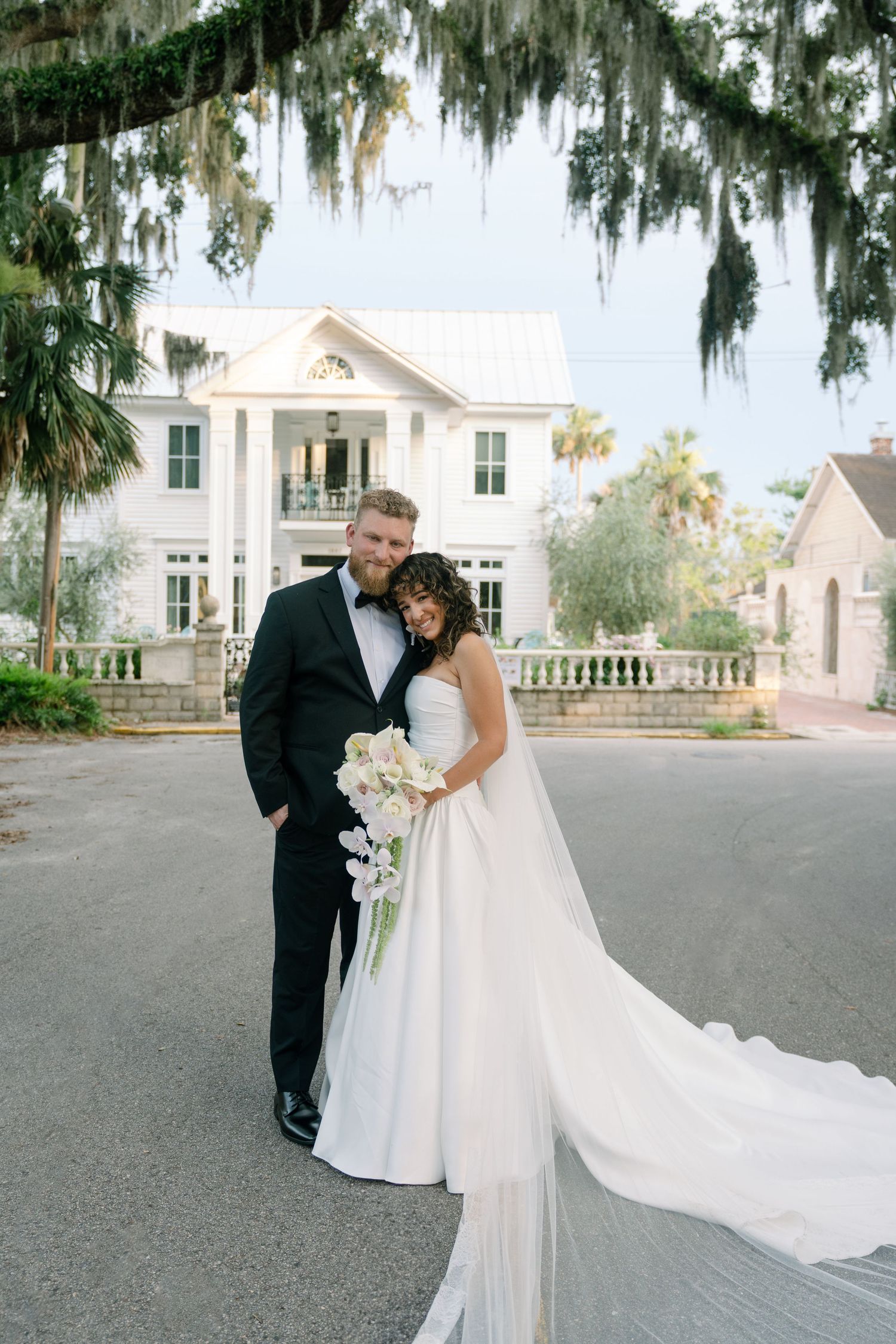 Elegant wedding photo in front of a southern plantation house with Spanish moss hanging from trees.