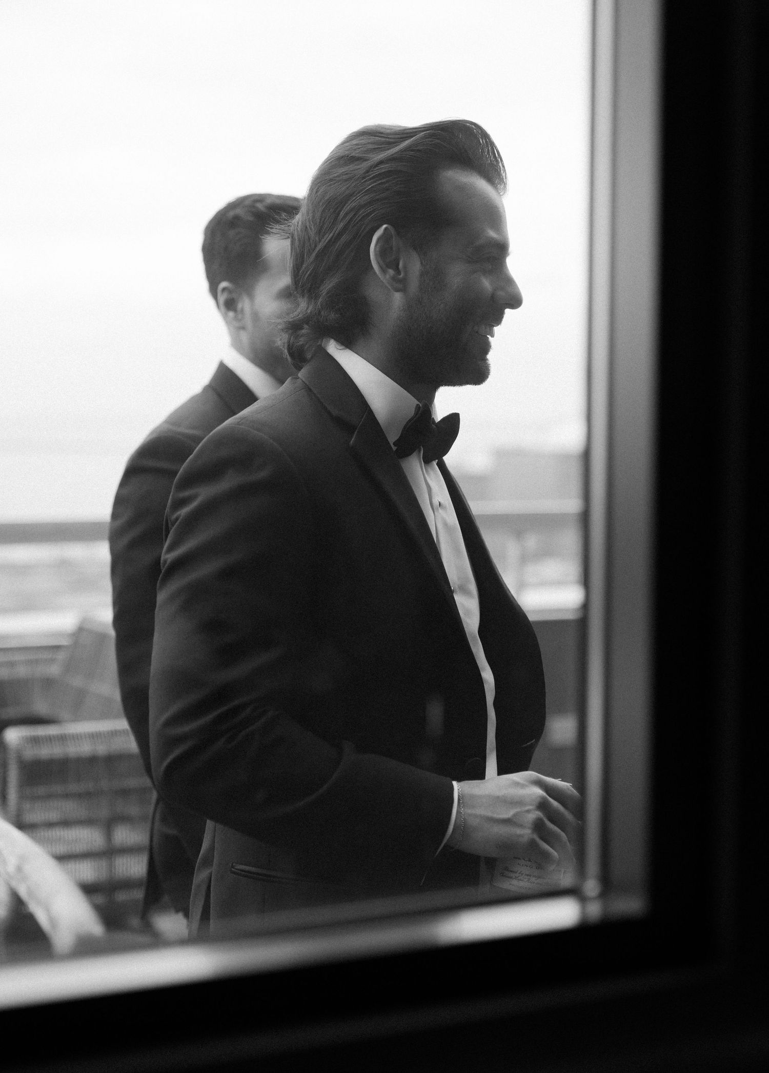 Series of silhouetted men in suits looking out large windows in black and white.