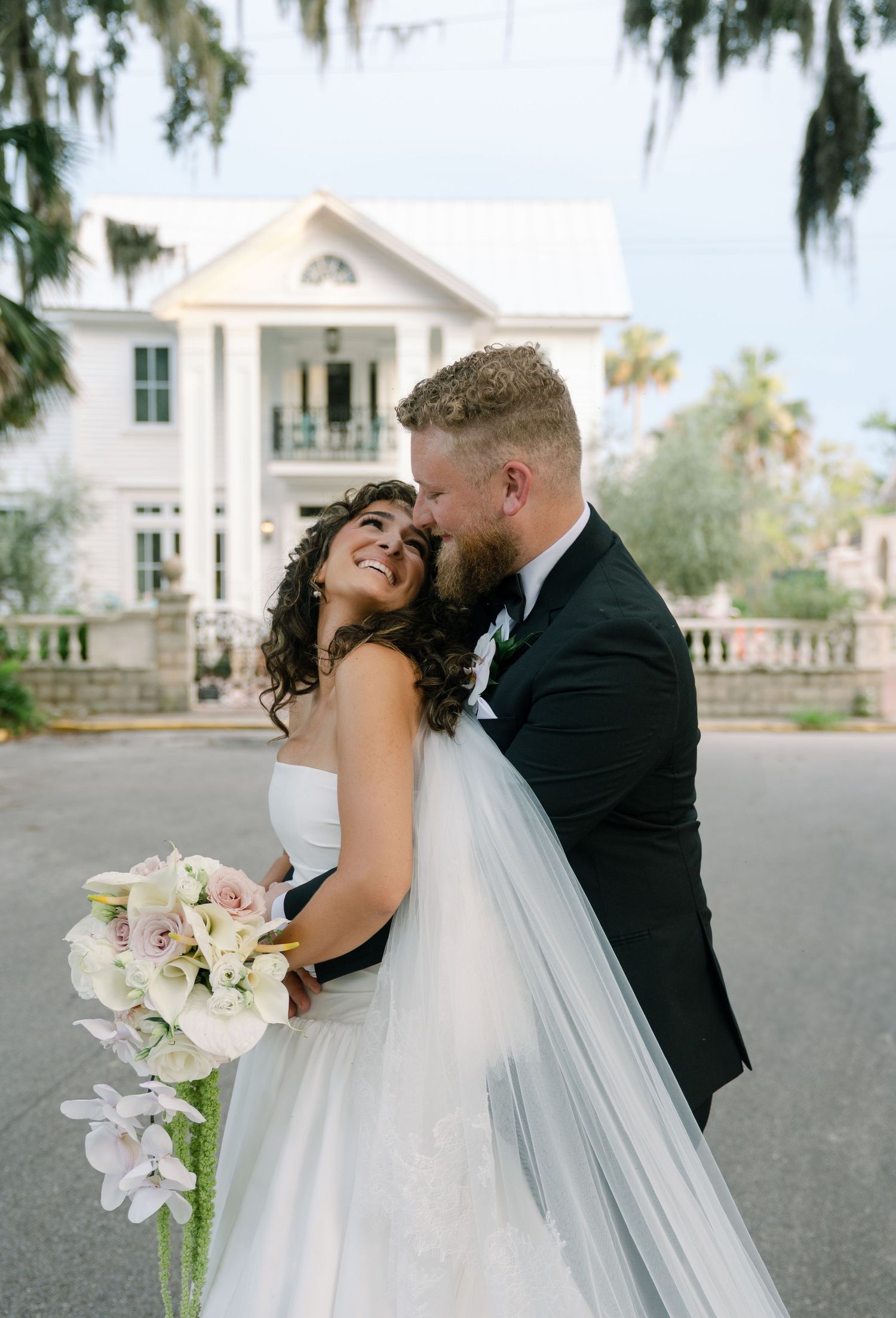 A romantic wedding portrait in front of a southern plantation-style mansion.