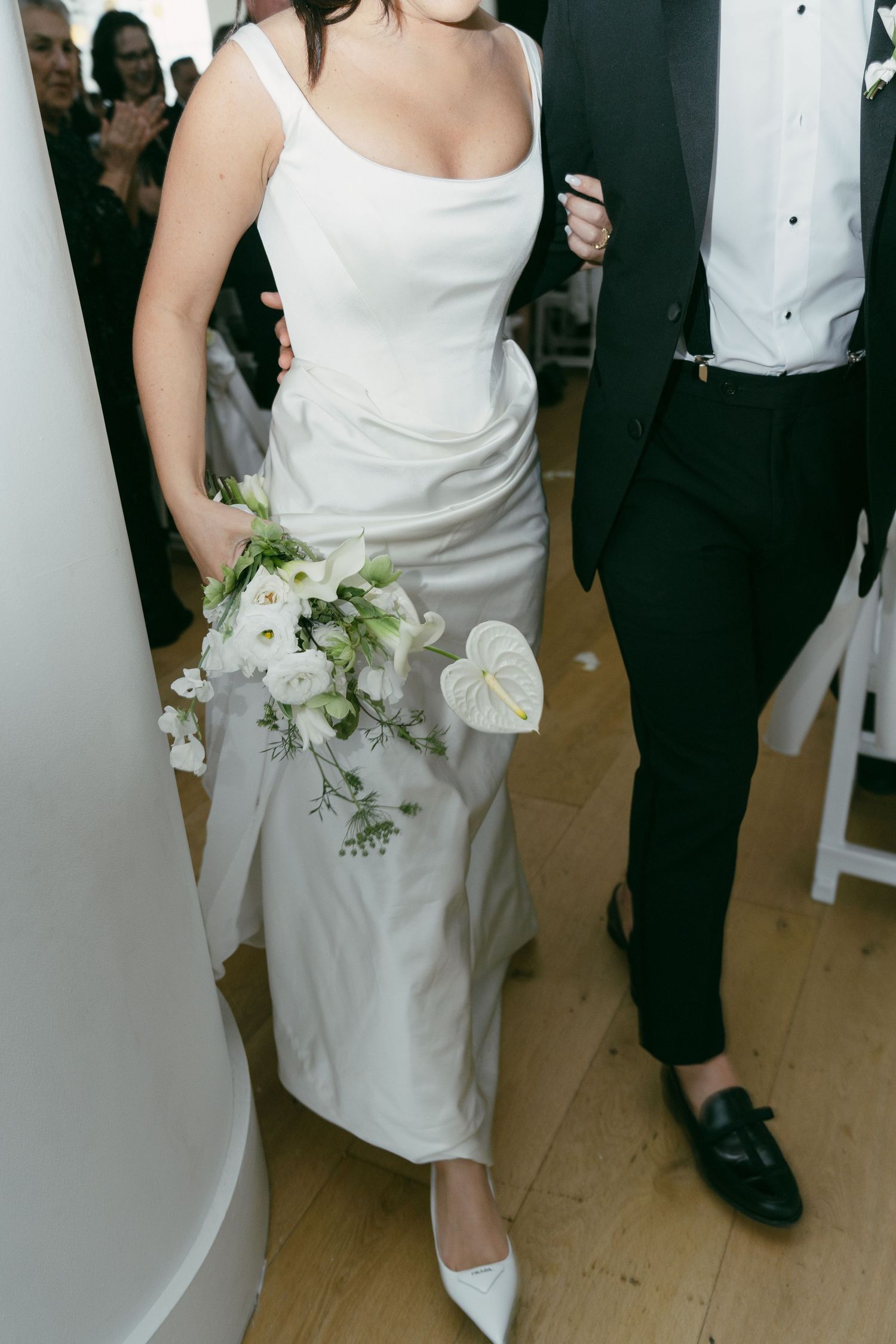 A white wedding dress with elegant floral bouquet featuring anthurium flowers and greenery.