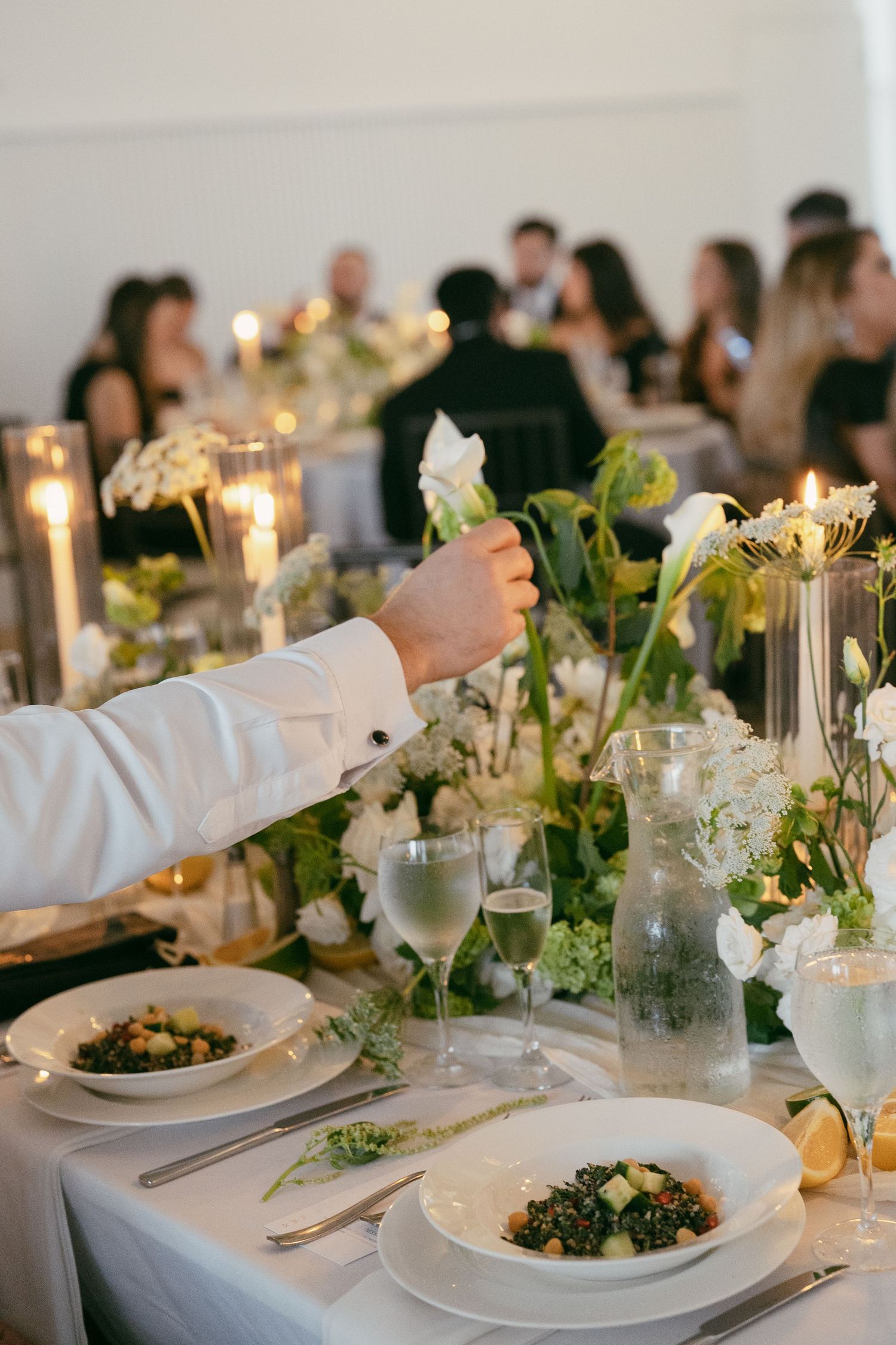 Elegant wedding reception table setting with candlelight, floral arrangements, and plated dinner service.