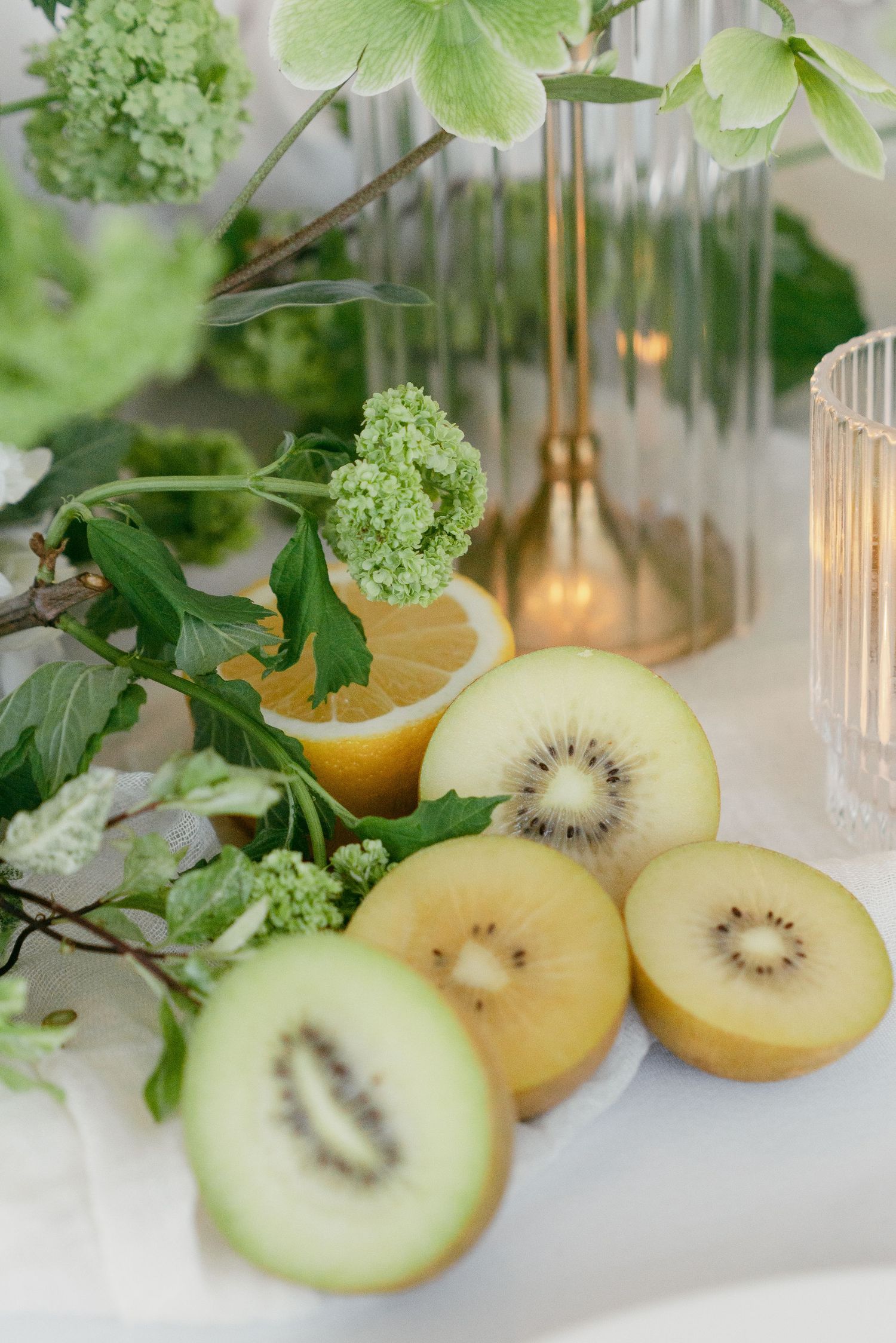 Fresh kiwi slices and green floral arrangements on an elegant table setting.