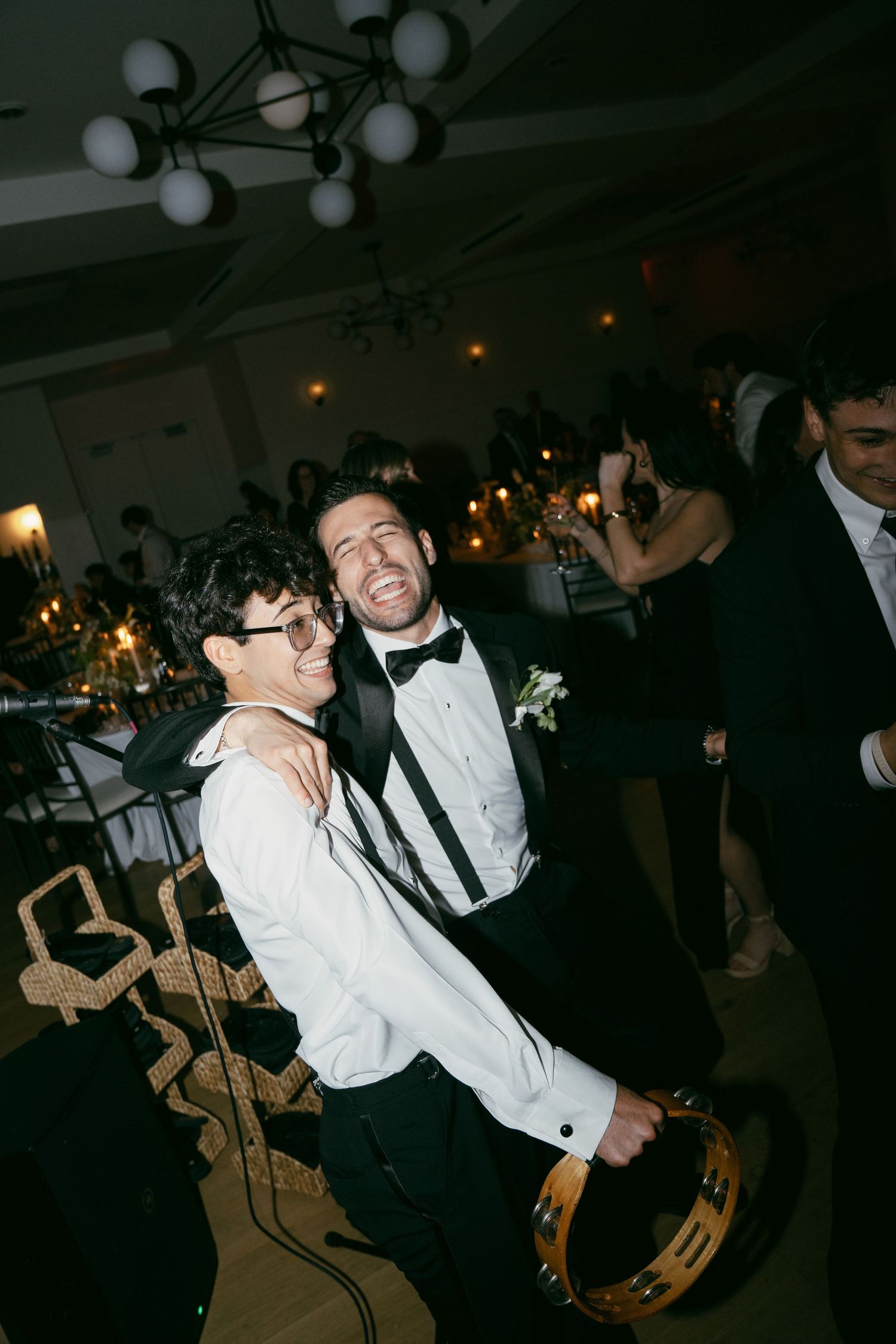 Two figures dance together enthusiastically at a formal event with one wearing white and one in black attire.