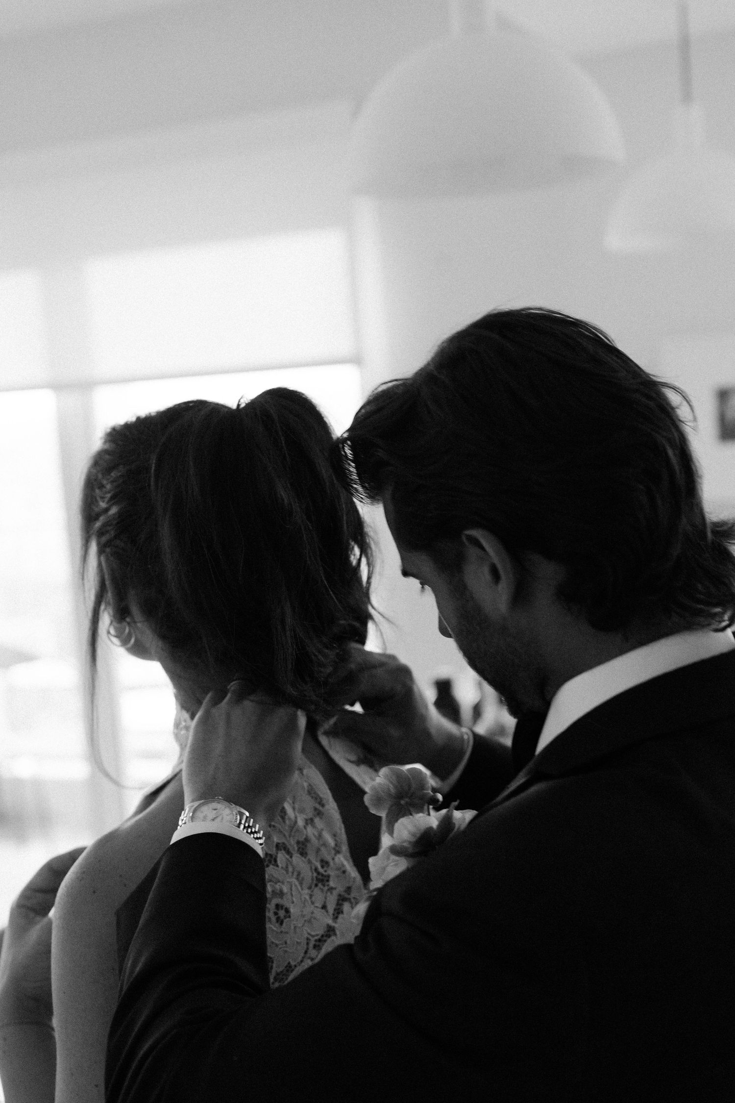 Silhouetted profiles of a couple in an emotional wedding moment against bright windows.