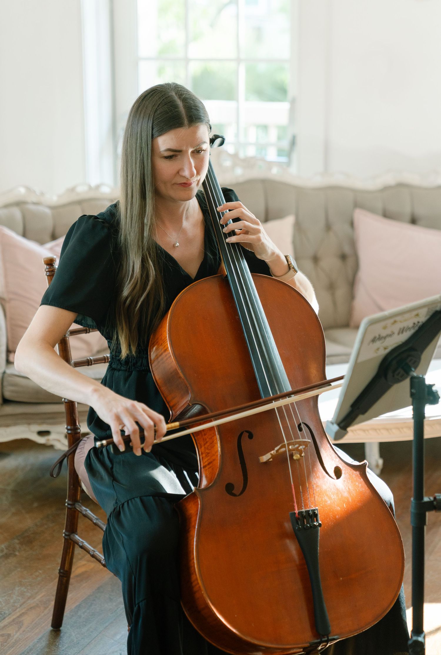 A cellist performs in an elegant room with soft natural lighting.