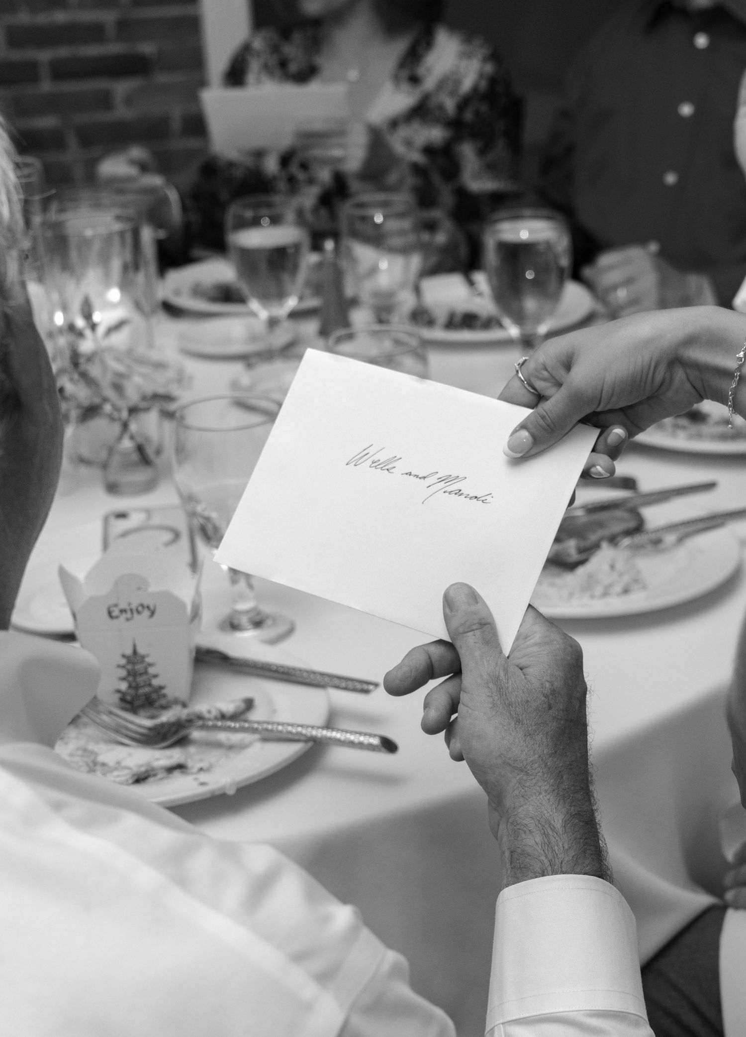 Hands holding a wedding place card at an elegant reception table setting.