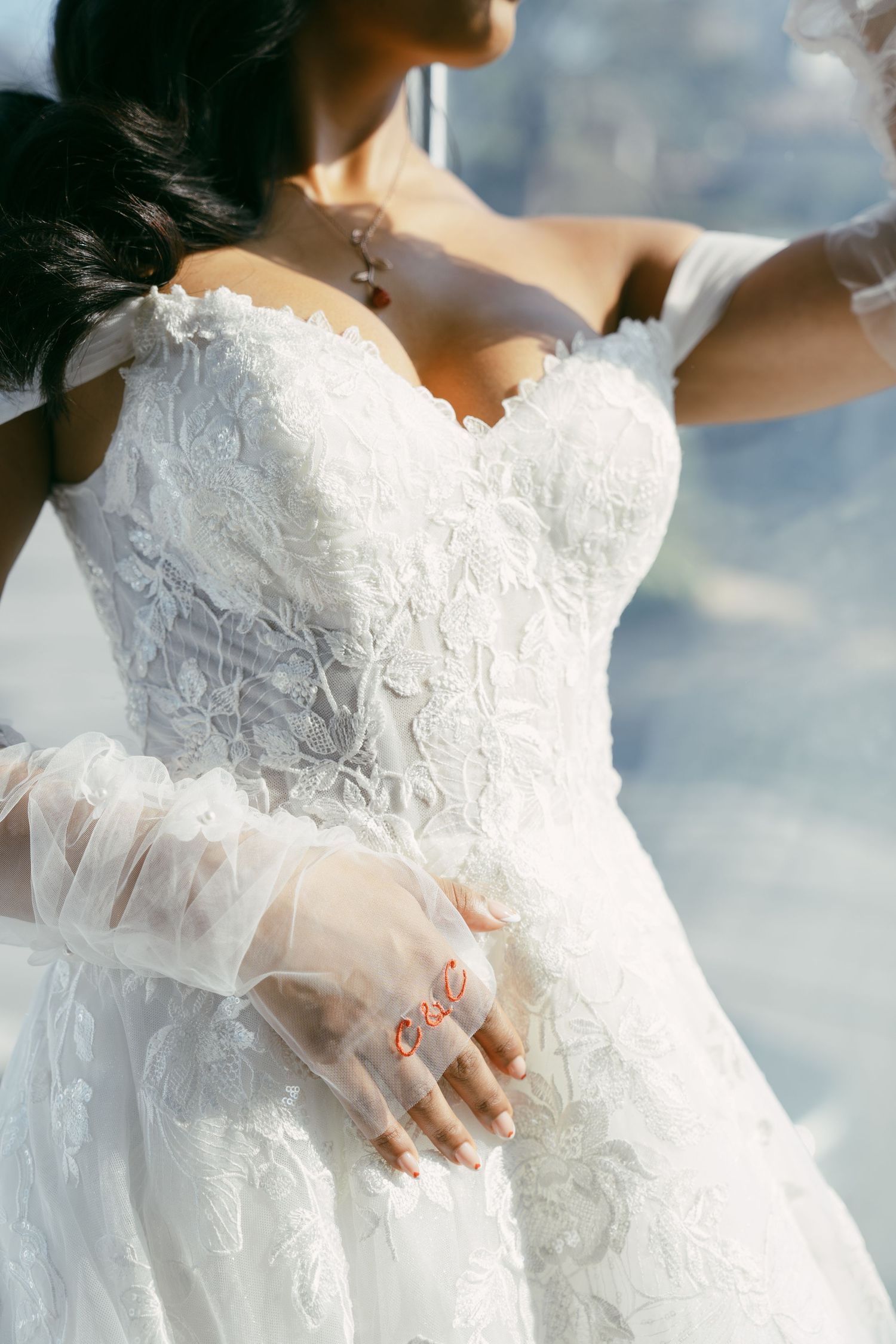 Close-up detail of a white lace wedding dress bodice with sheer sleeves.