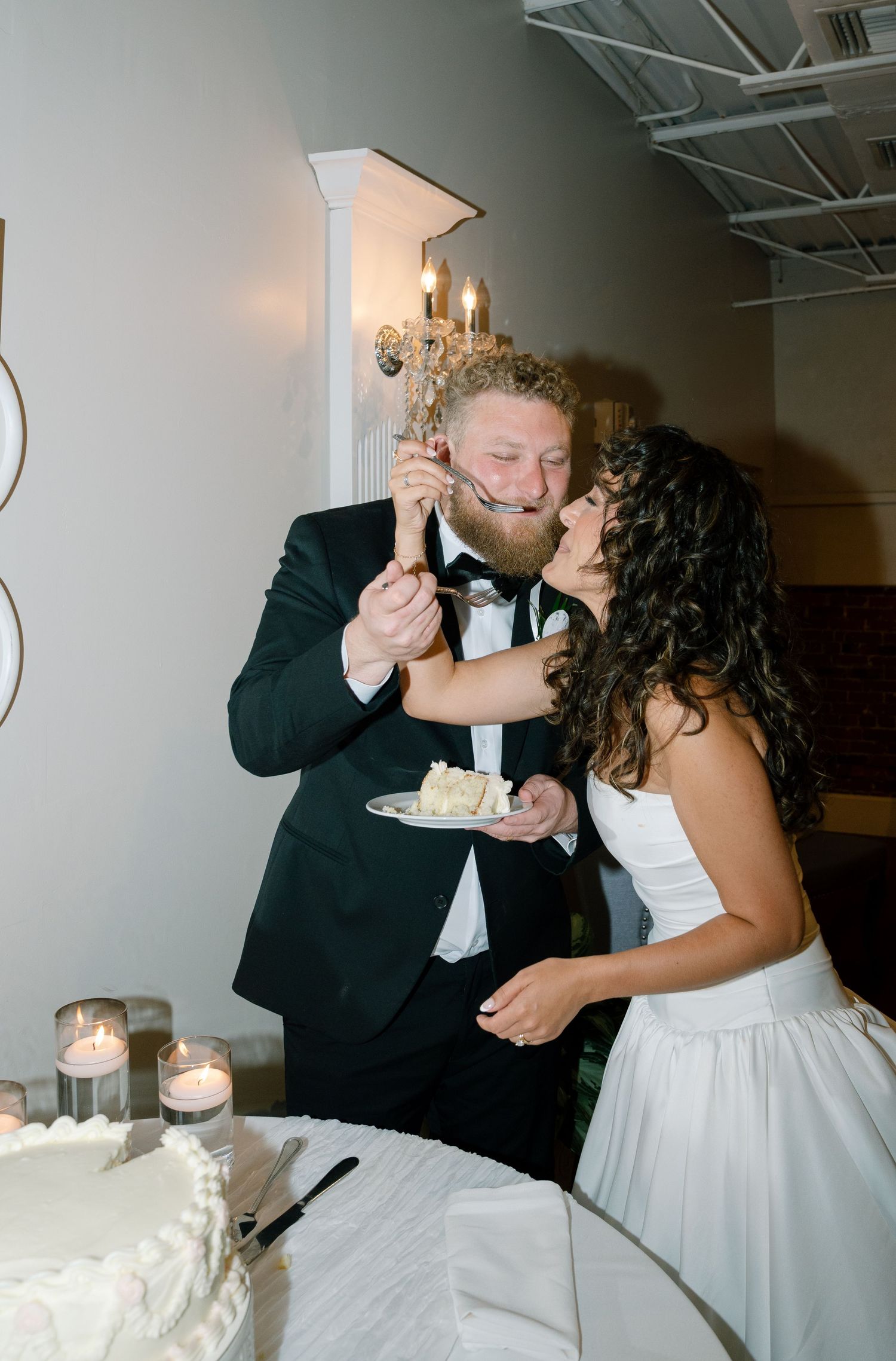 A couple shares a playful moment while cutting their wedding cake together.