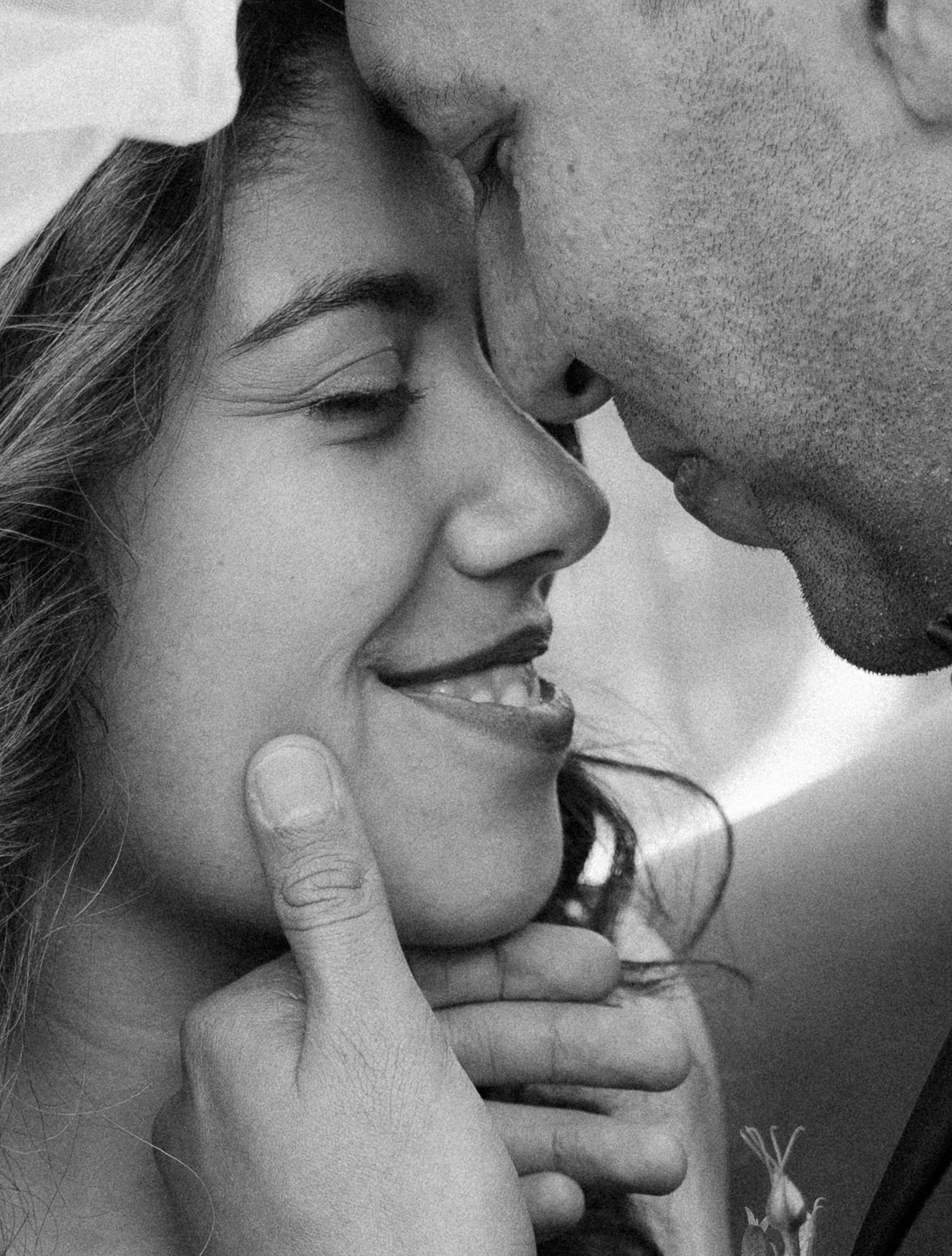 A tender moment between a couple sharing an intimate close-up in black and white.