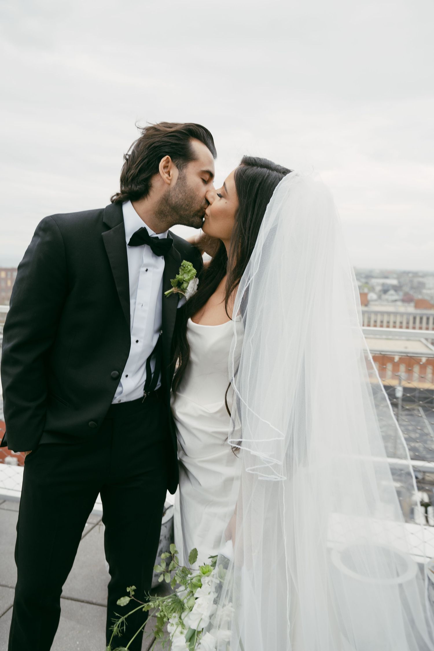 Romantic rooftop wedding photos of couple sharing intimate moments against city skyline.