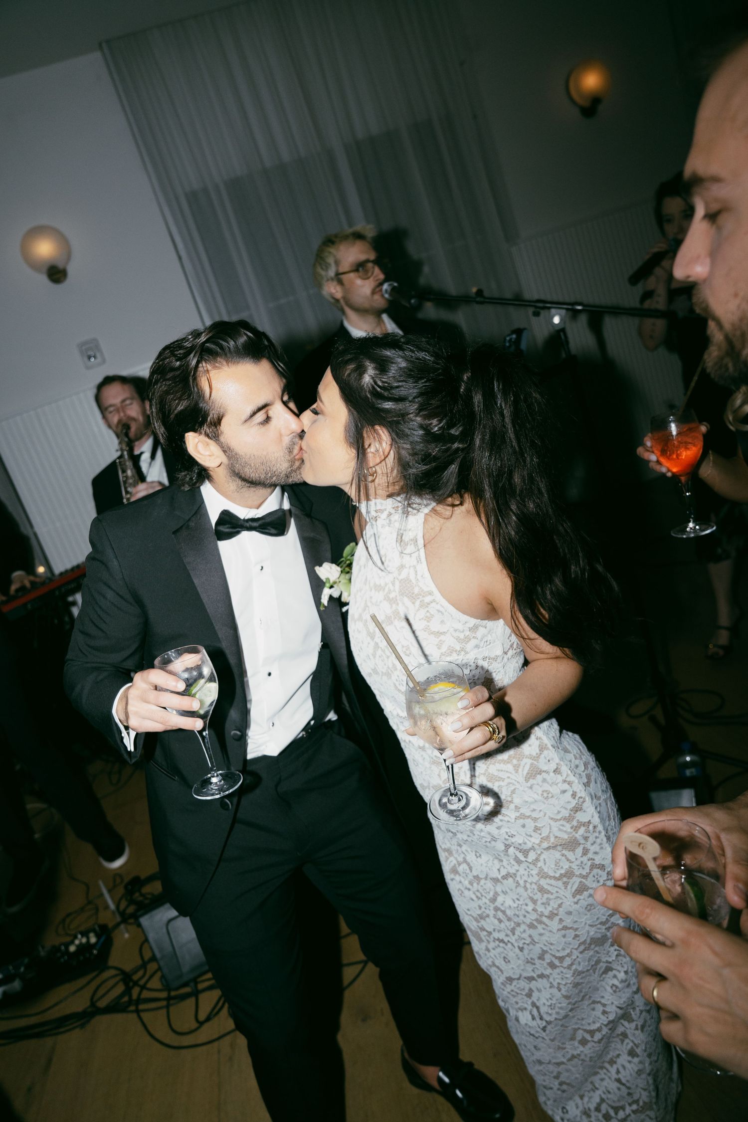 Wedding couple sharing a romantic moment with drinks on a dimly lit dance floor.