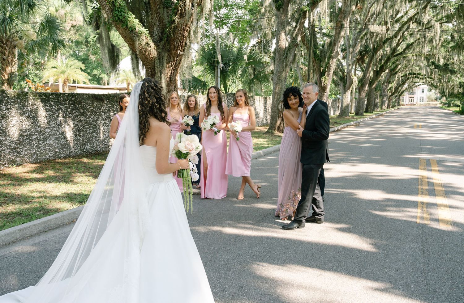 Wedding party gathers on a Spanish moss-draped pathway for photos.