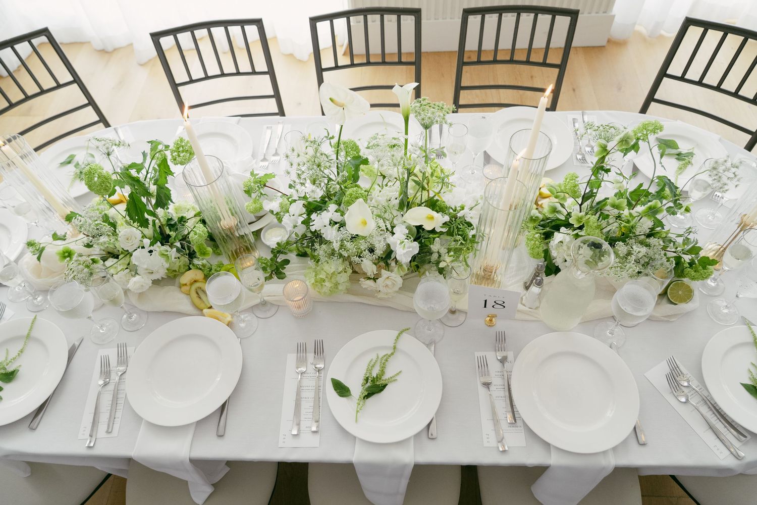 Elegant wedding table setting with white floral centerpieces and chiavari chairs.