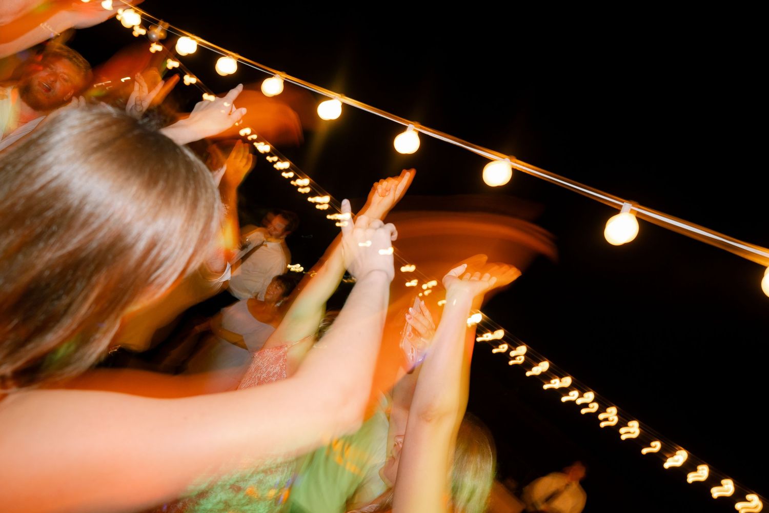 String lights illuminating an outdoor evening wedding celebration.