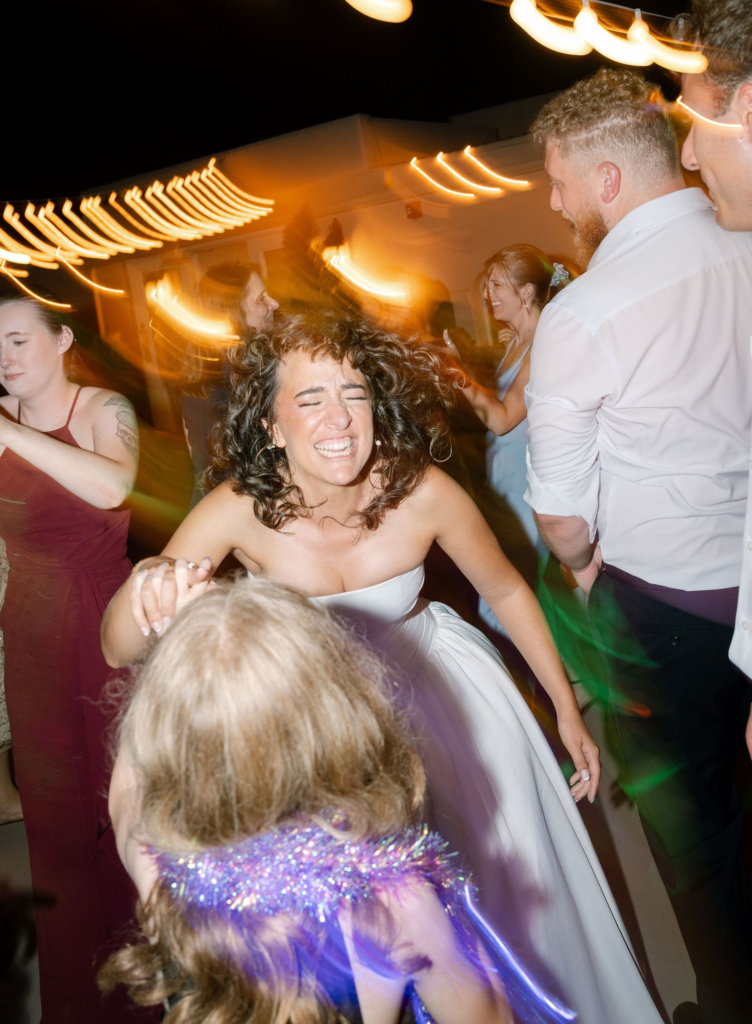 Energetic dancing and celebration moments captured at a nighttime wedding reception.