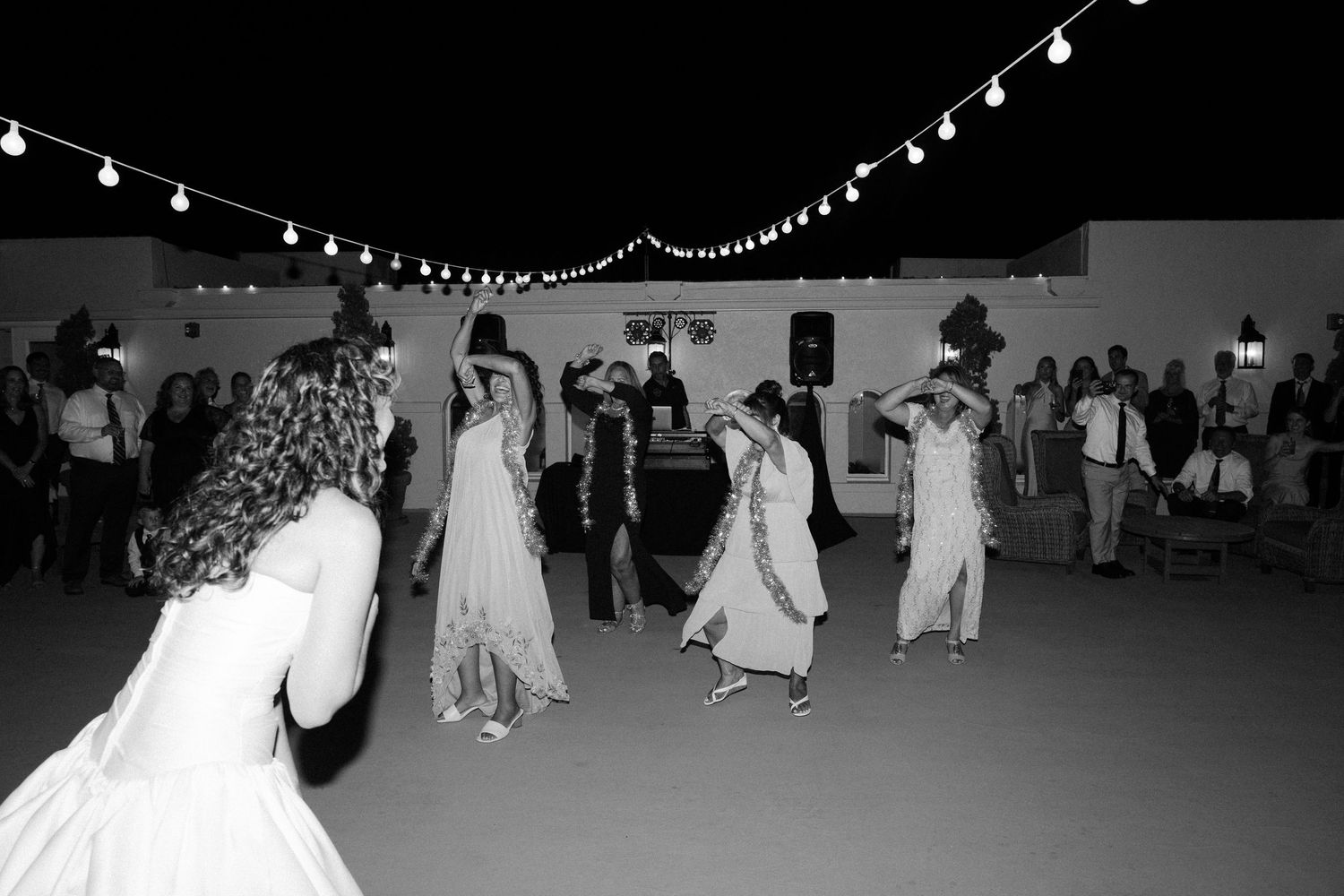 Black and white photo of wedding reception dancing under string lights.