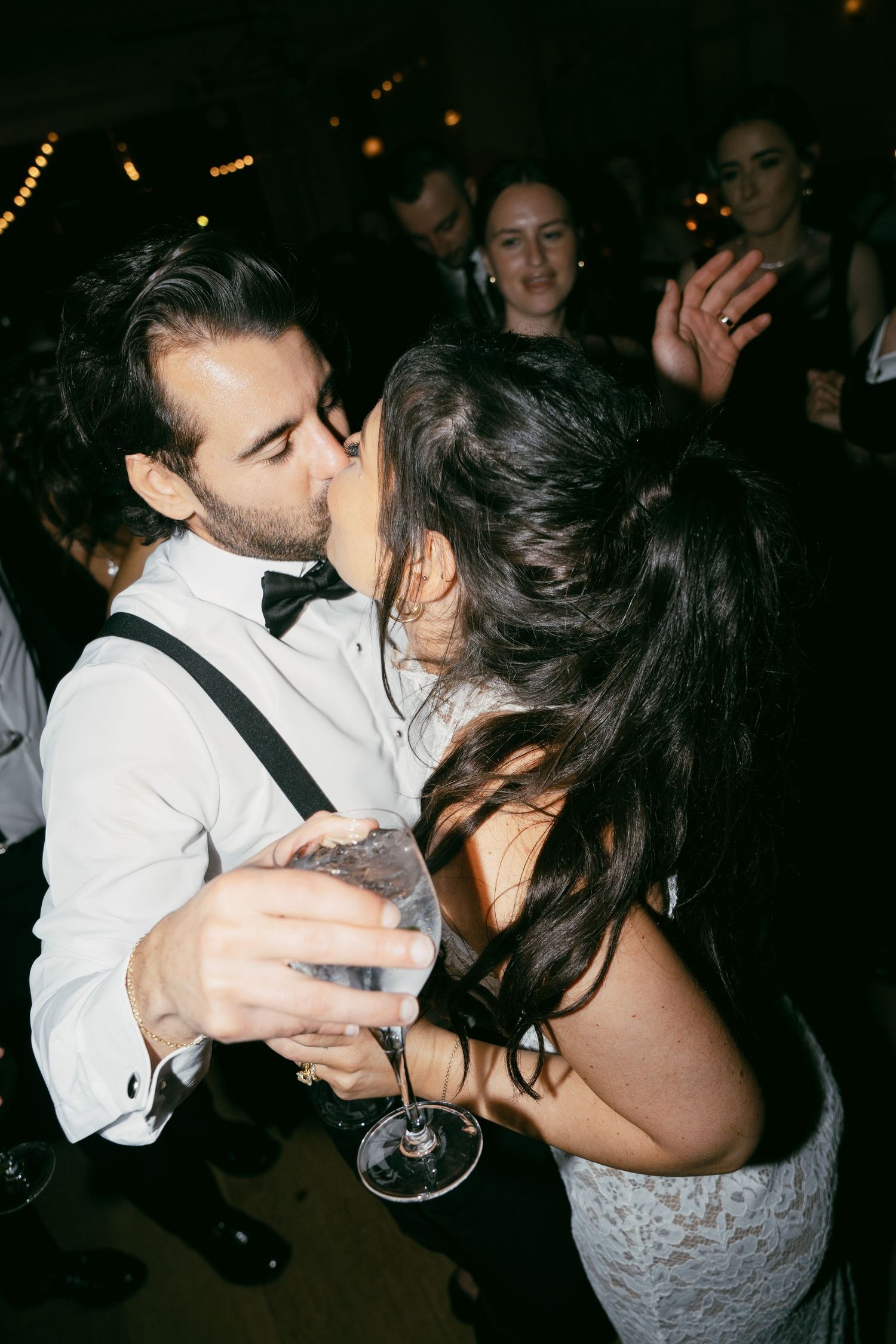 Couple sharing an intimate dance while holding champagne glasses at their wedding reception.