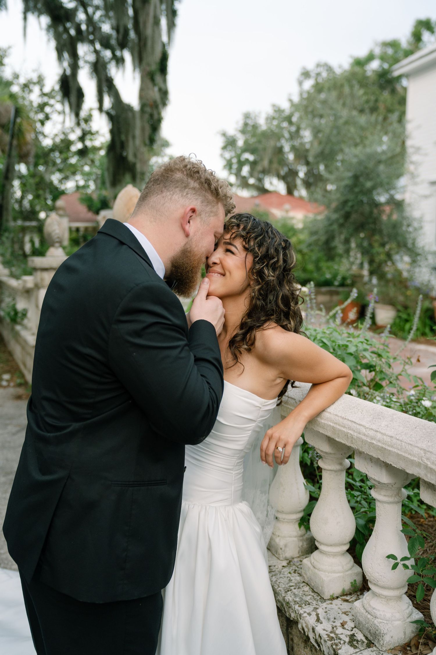 Intimate wedding moment captured on stone steps surrounded by lush southern greenery.