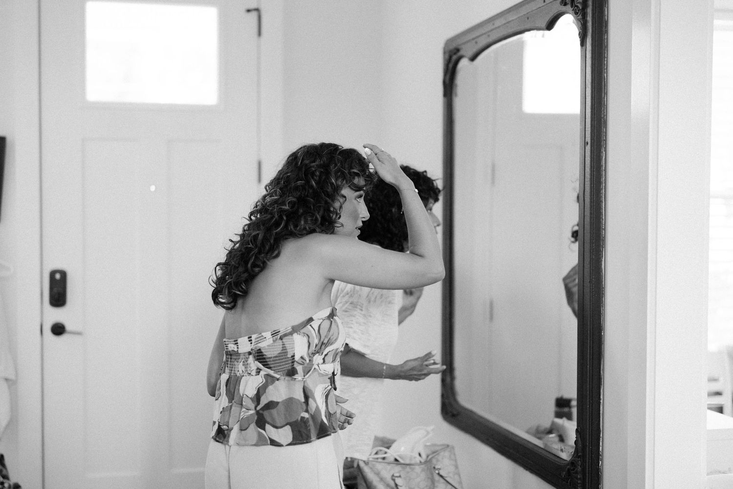 Black and white getting ready shots of wedding preparation in bright room with mirror.