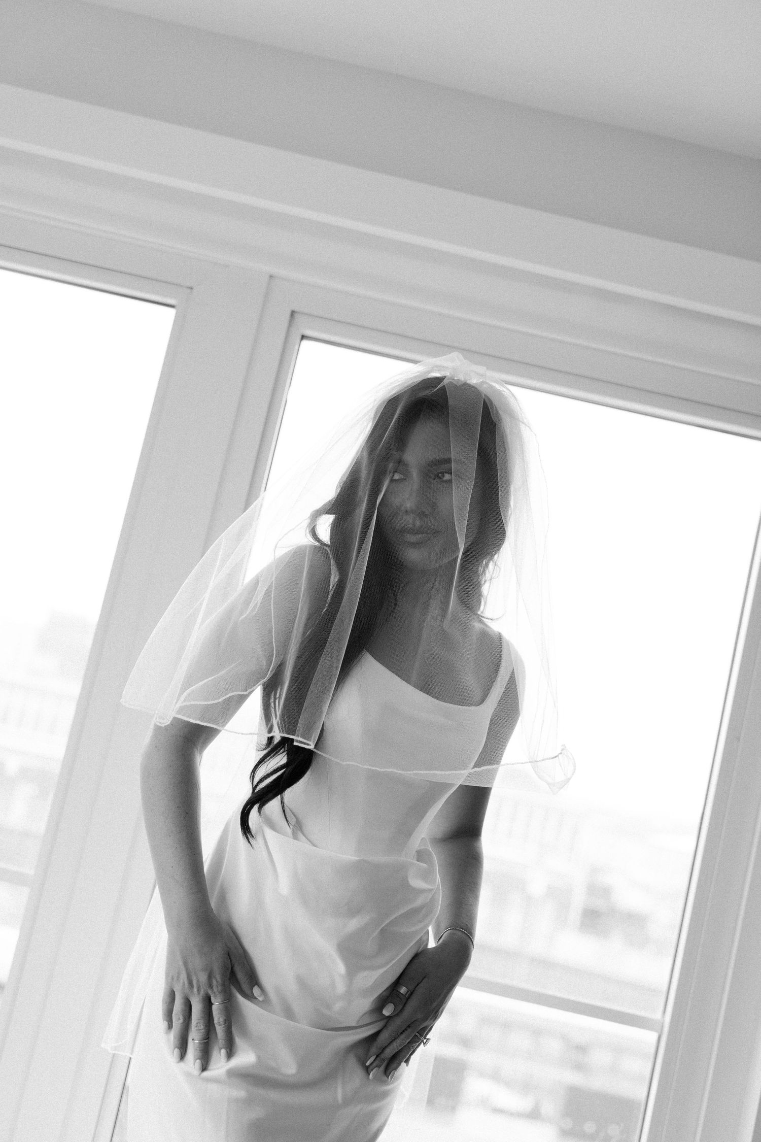 A dreamy window portrait of someone in a white dress with flowing veil.