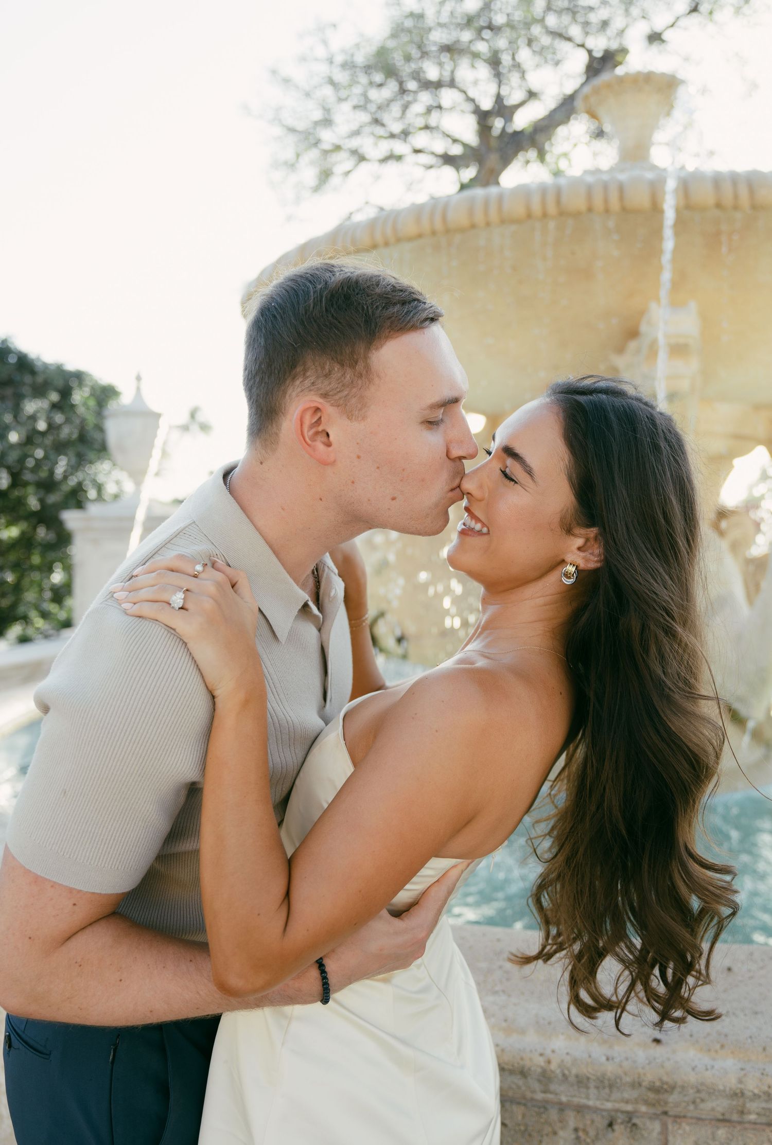Playful wedding couple laughing and embracing in outdoor garden setting.