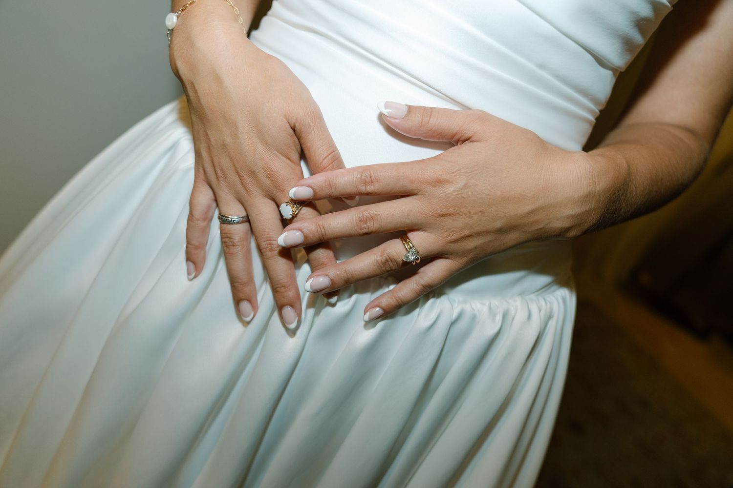 Detail shot of hands holding the waist of an elegant white wedding dress.