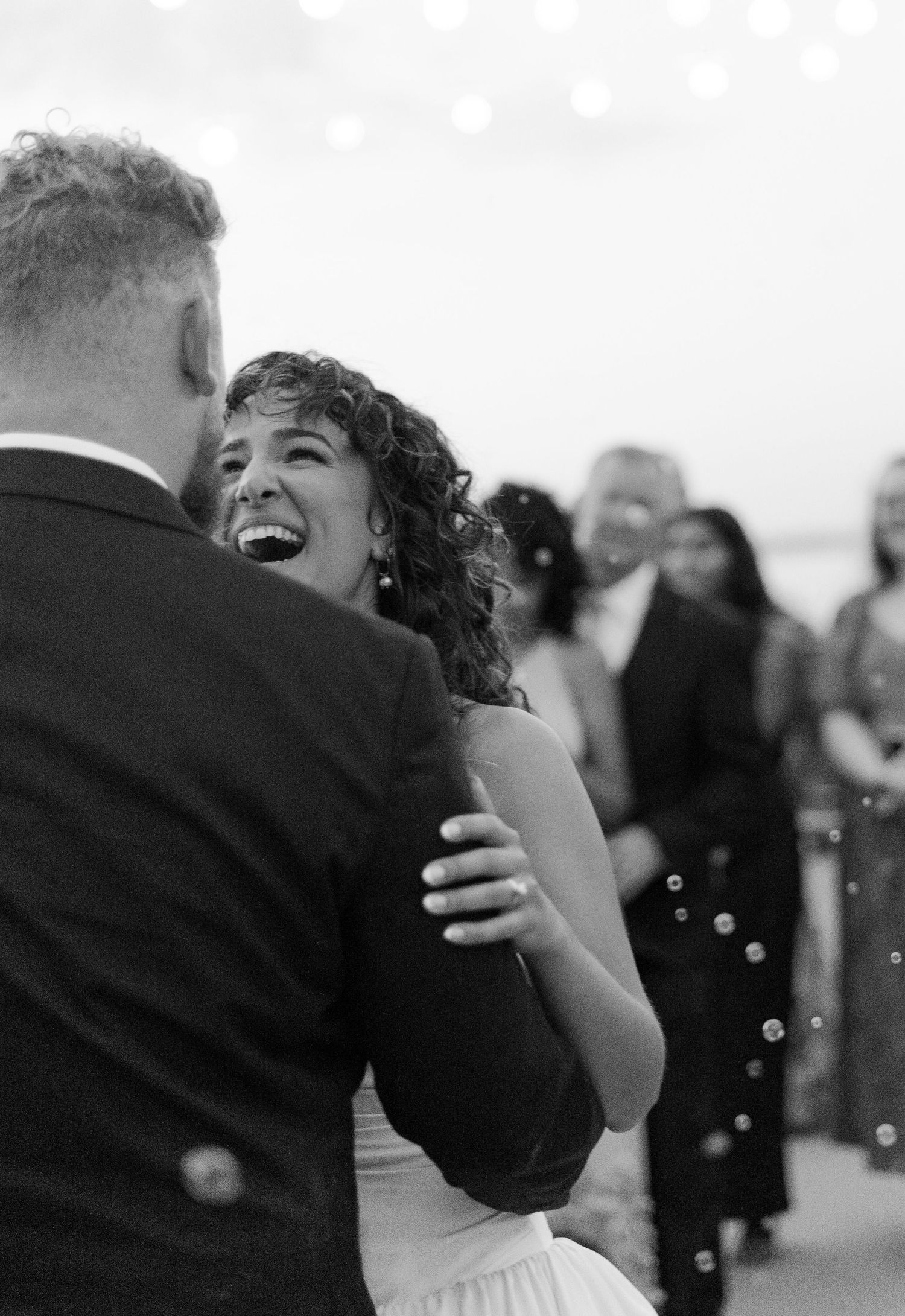 A black and white candid photo capturing a joyful dance moment at a wedding celebration.