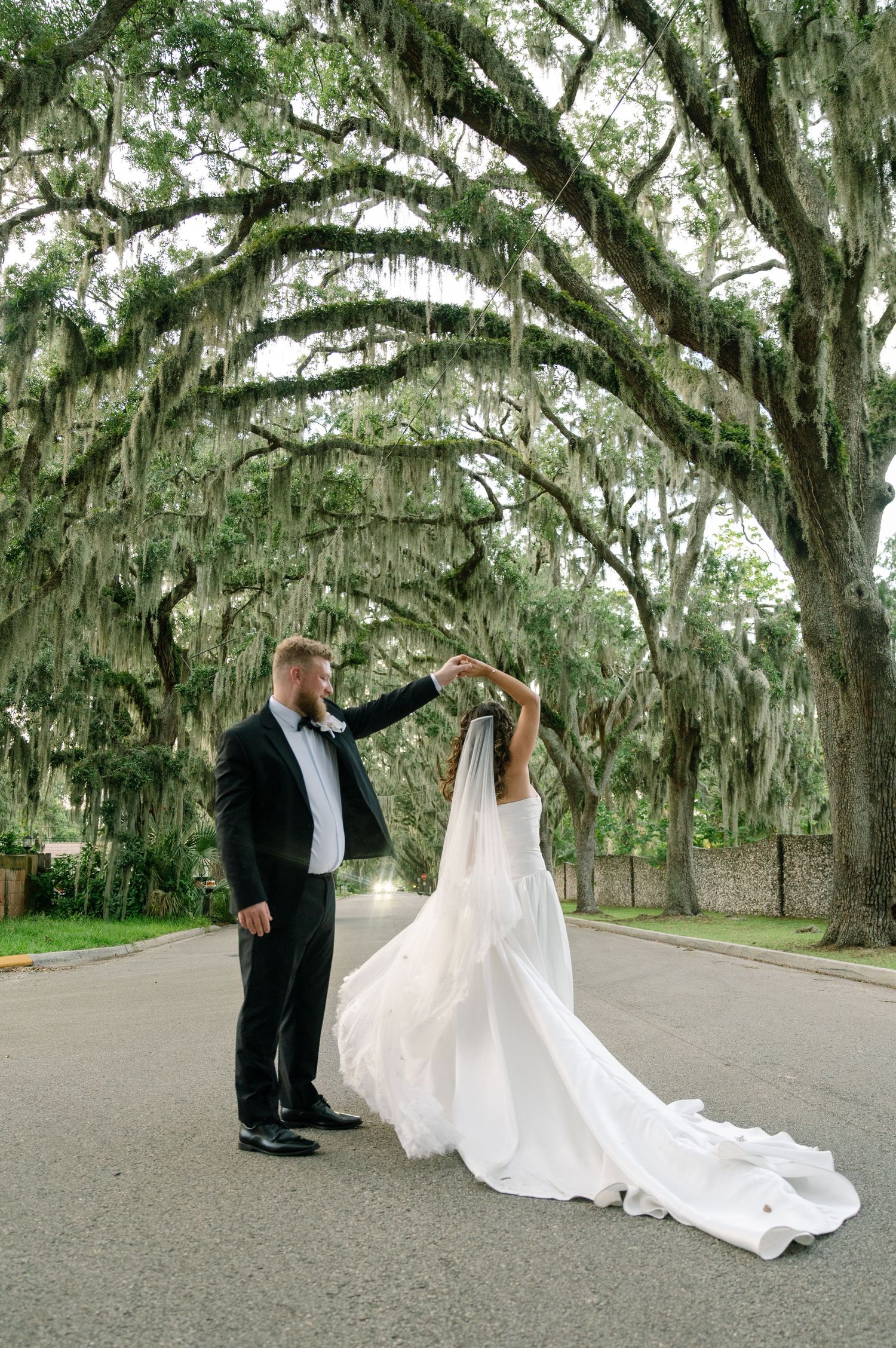 Couple dancing under a canopy of Spanish moss trees along a scenic southern road.