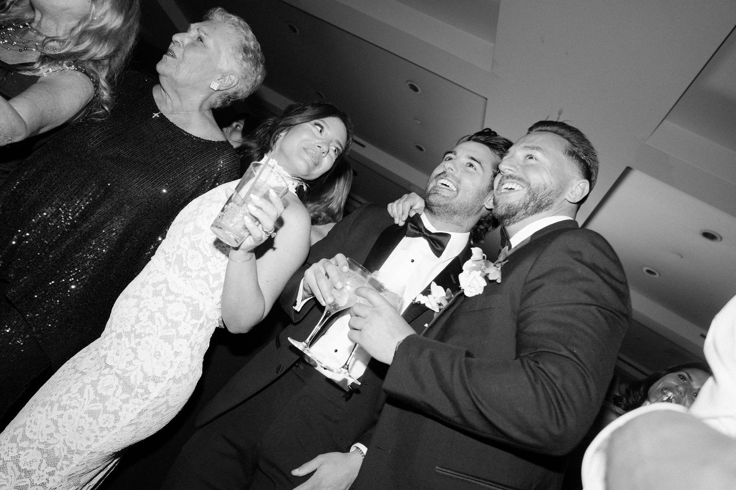 Wedding party guests dancing and celebrating at a reception in black and white photography.