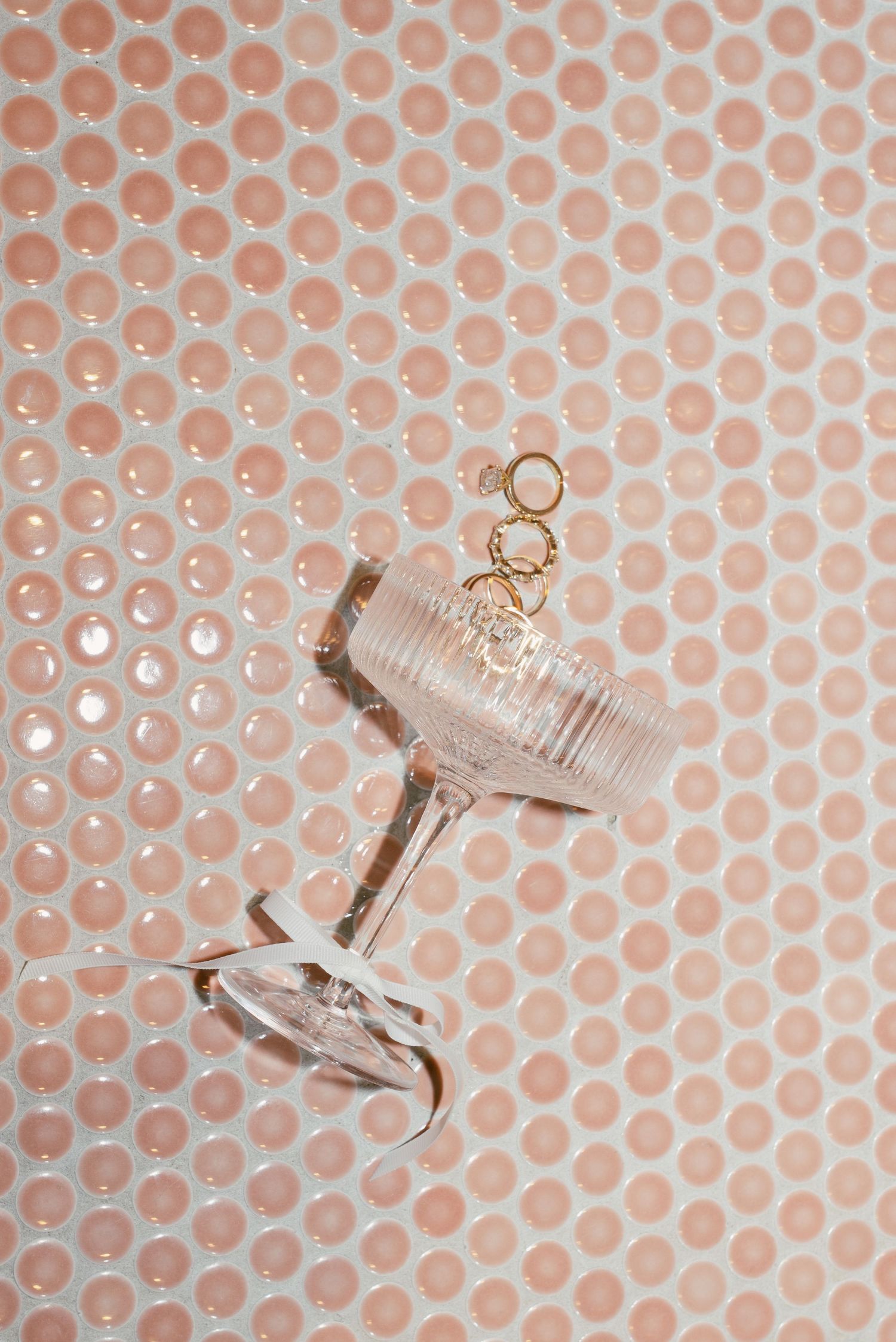 A vintage crystal champagne coupe glass against a peach polka dot background.