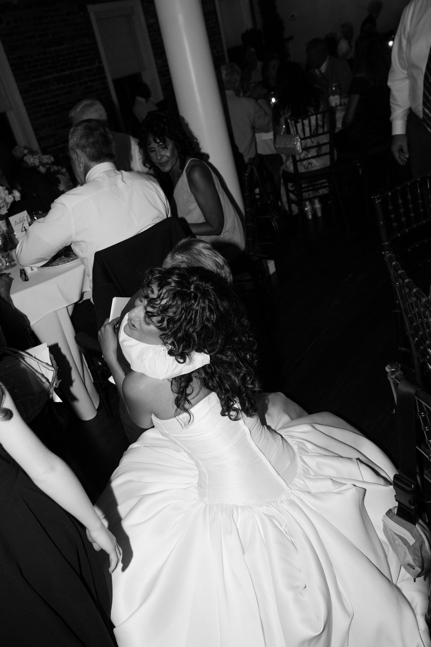 Black and white photo of wedding guests dancing at a lively reception.