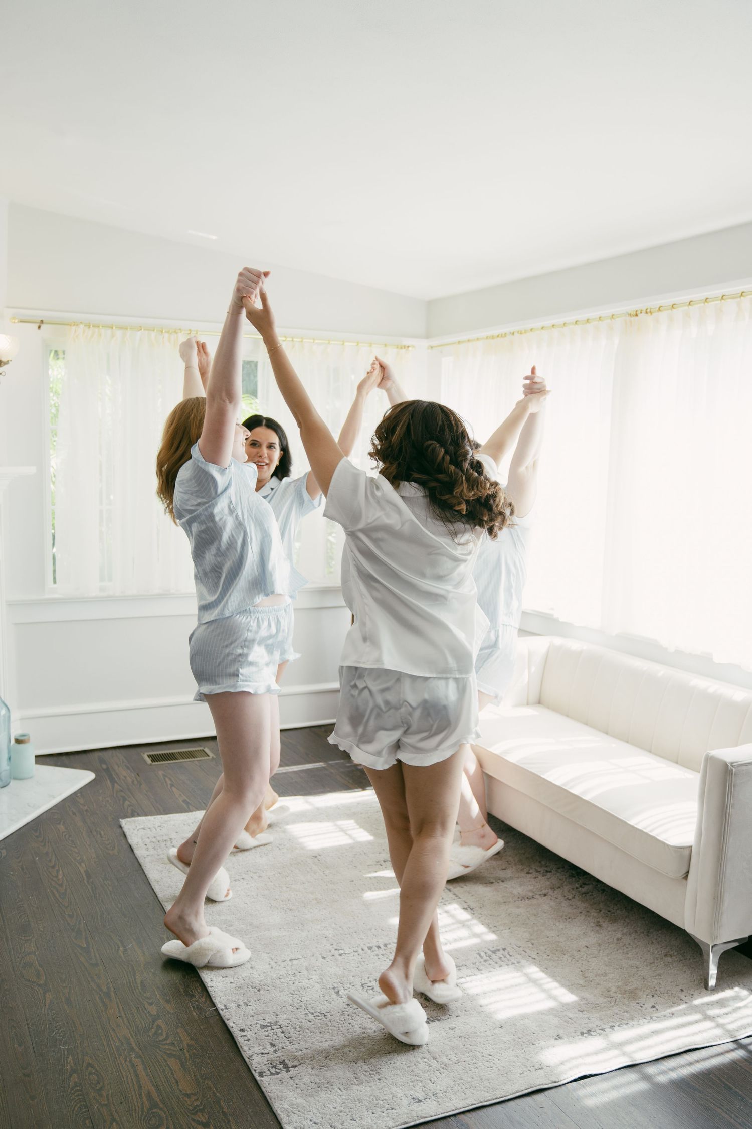 Two people dancing joyfully in matching white sleepwear in a sunlit room.