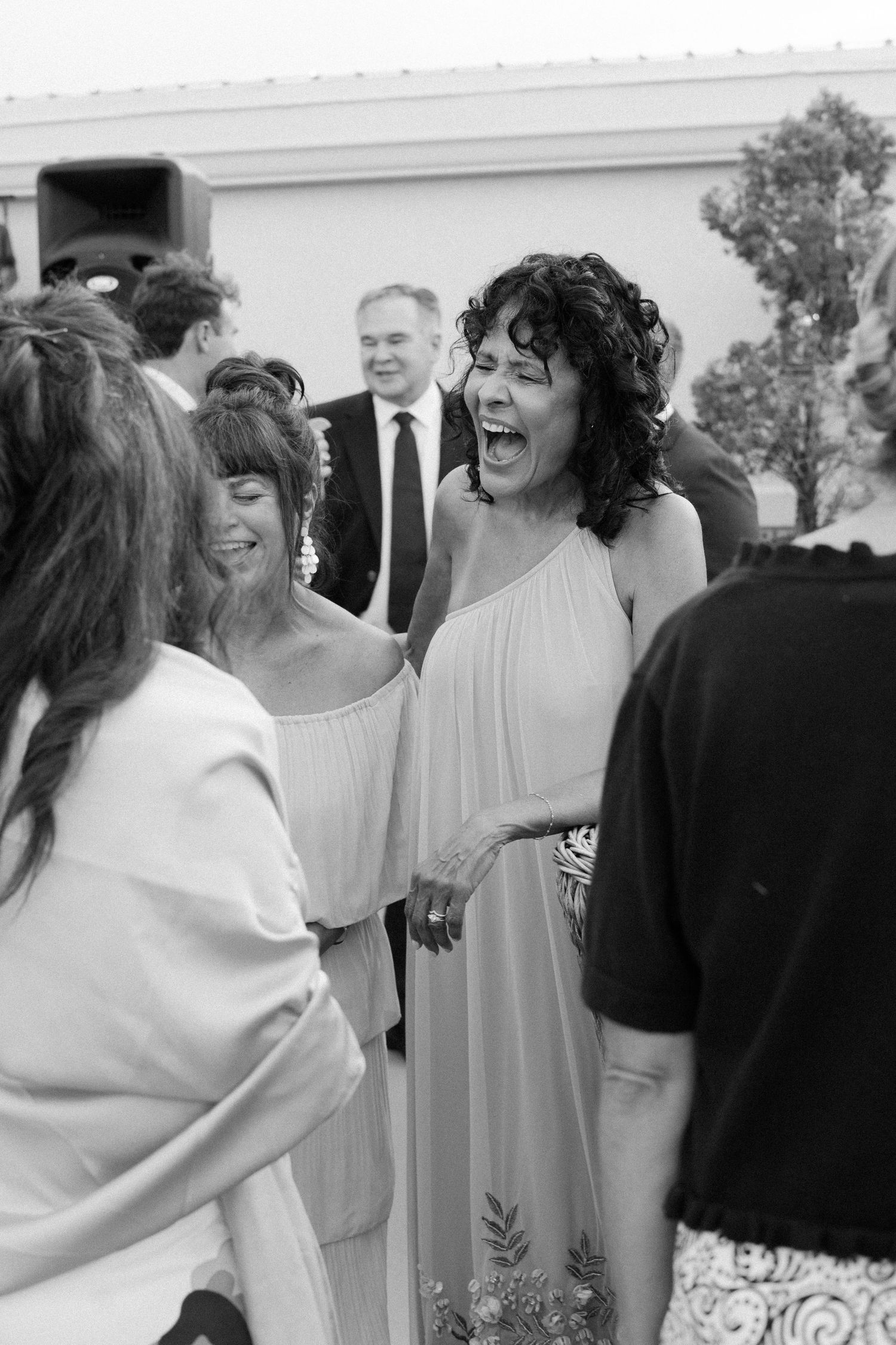 Wedding guests sharing joyful laughter at an outdoor reception.