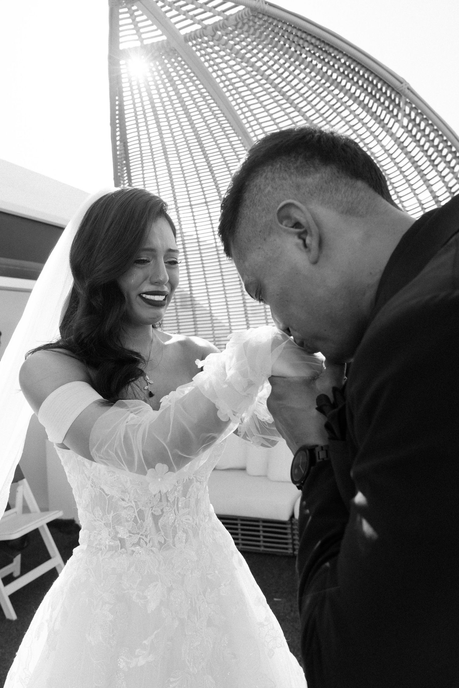 Wedding moment captured under modern architecture with dramatic sunlight.