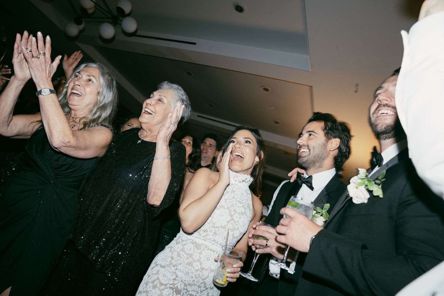 Wedding guests and newlyweds celebrate enthusiastically during a reception party.