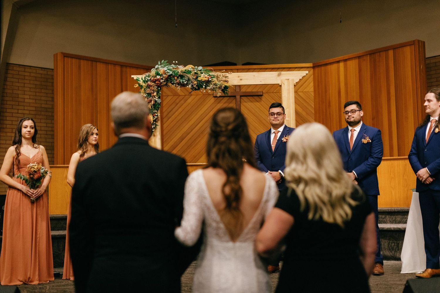 bride walking down the isle to her groom with her parents by her side