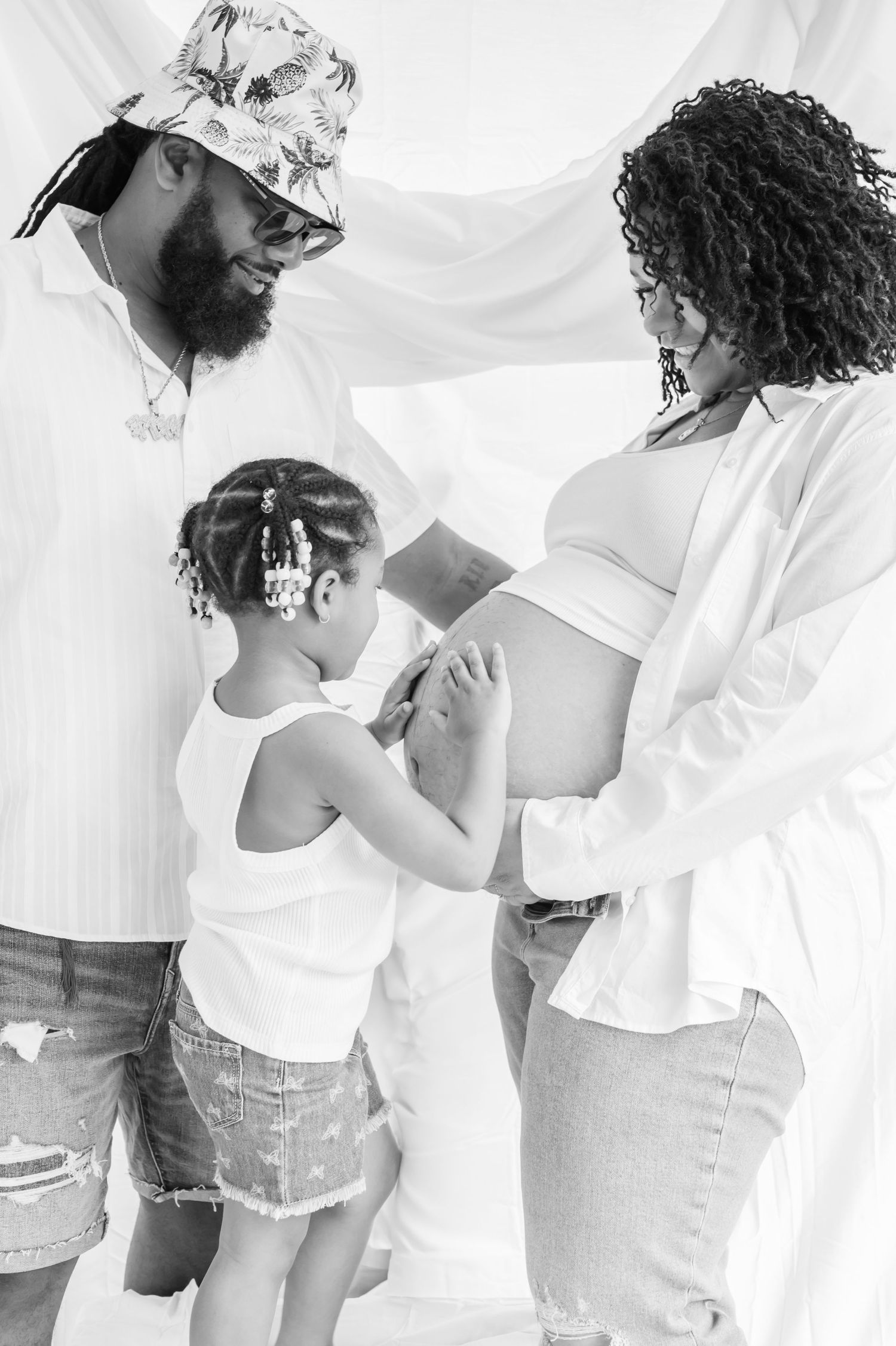 A beautiful black and white maternity photoshoot featuring a family of three sharing an intimate moment together.